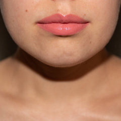 Lip gloss with peach color and glossy finish on lips