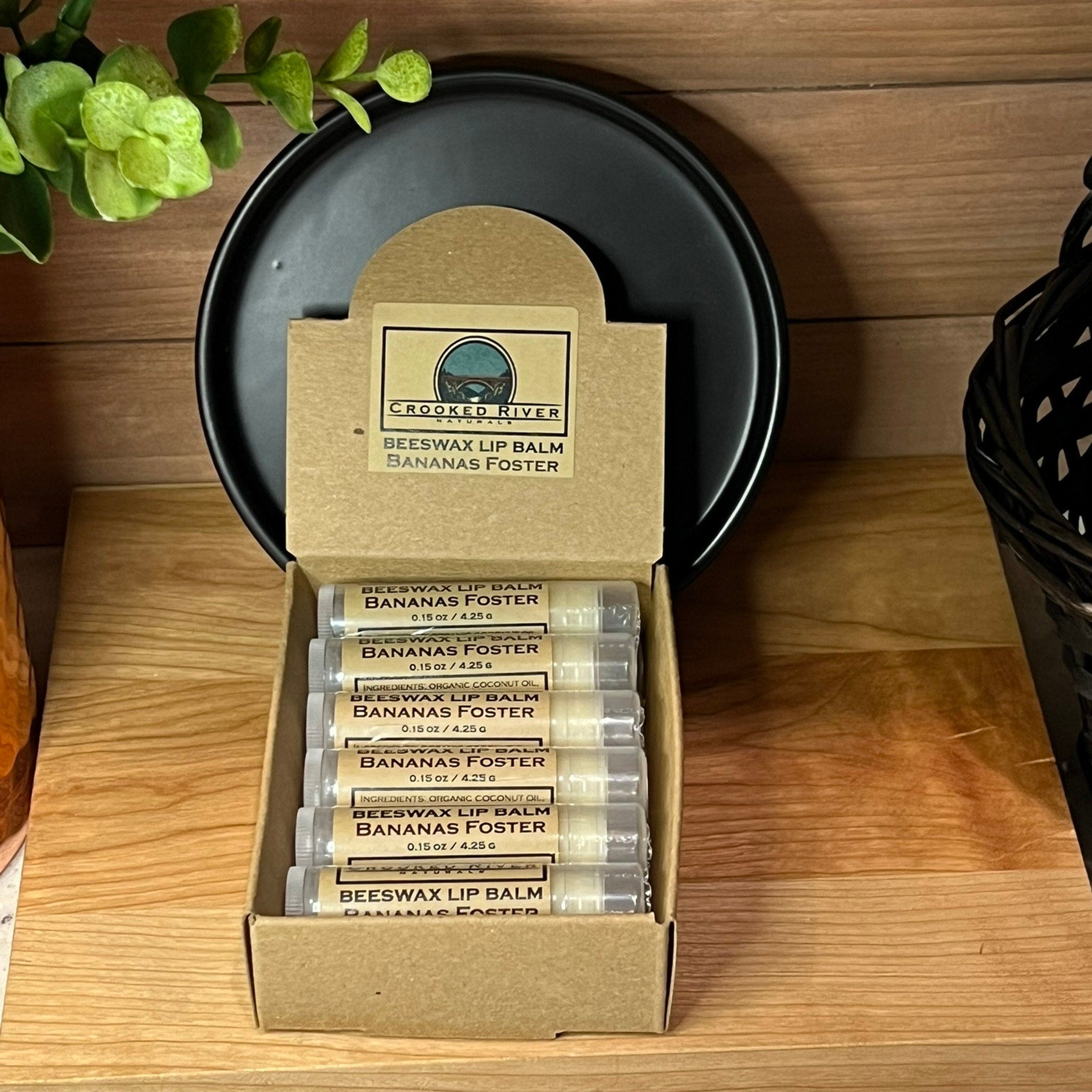 Beeswax lip balm tubes in clear plastic, with brown and white labels, inside a cardboard box, Crooked River brand visible
