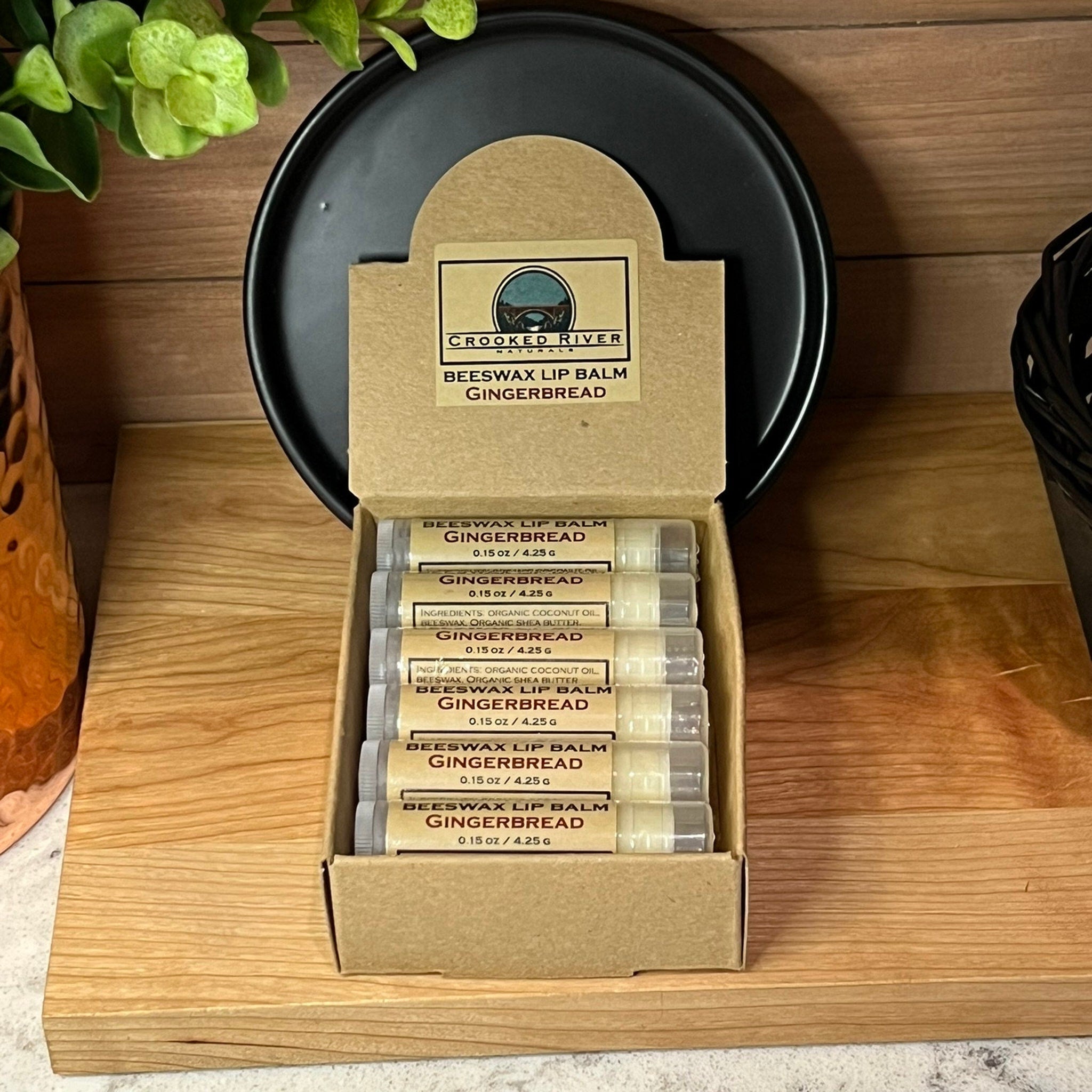 Beeswax lip balm tubes in cardboard box, with Crooked River branding, on wooden surface