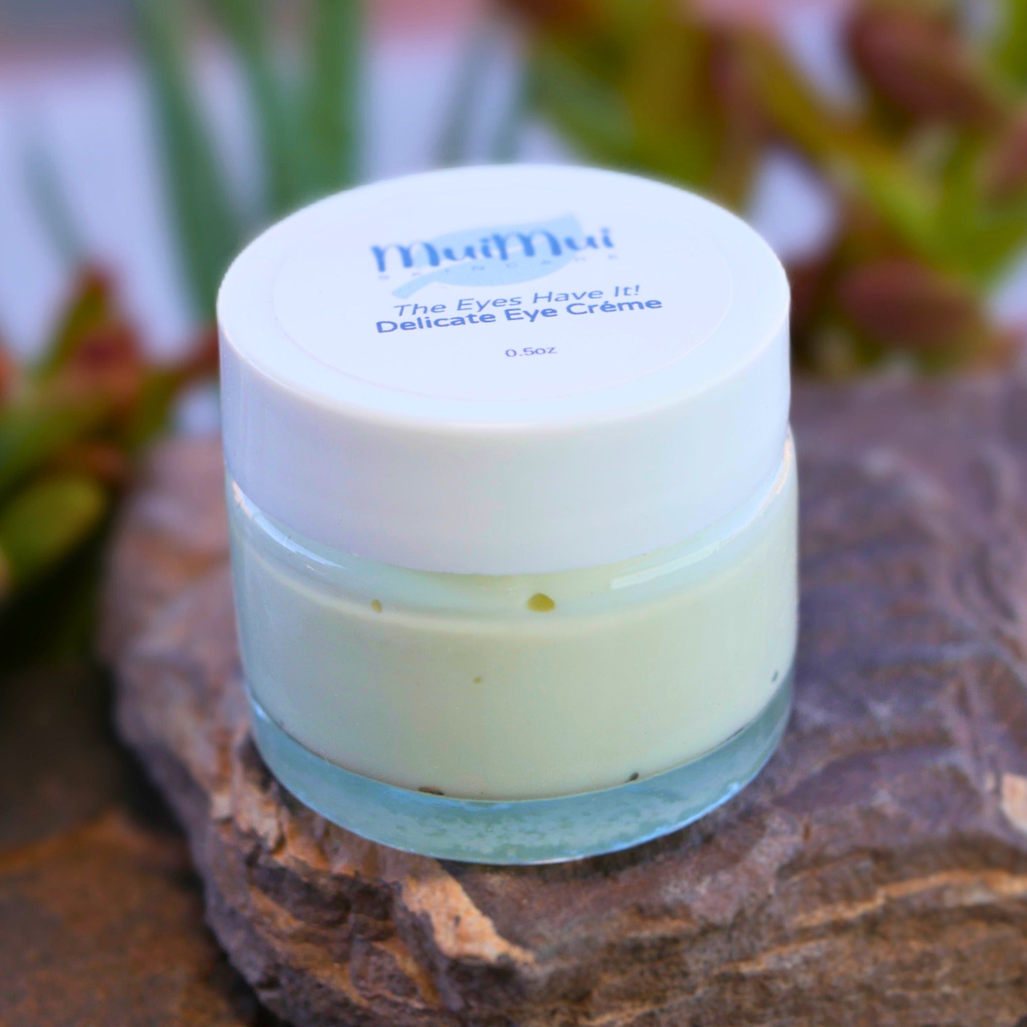 Eye cream jar with white lid, clear glass, and pale green cream, MuiMui brand label visible