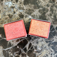 Matchboxes with red and orange textured surfaces, on a marble table.