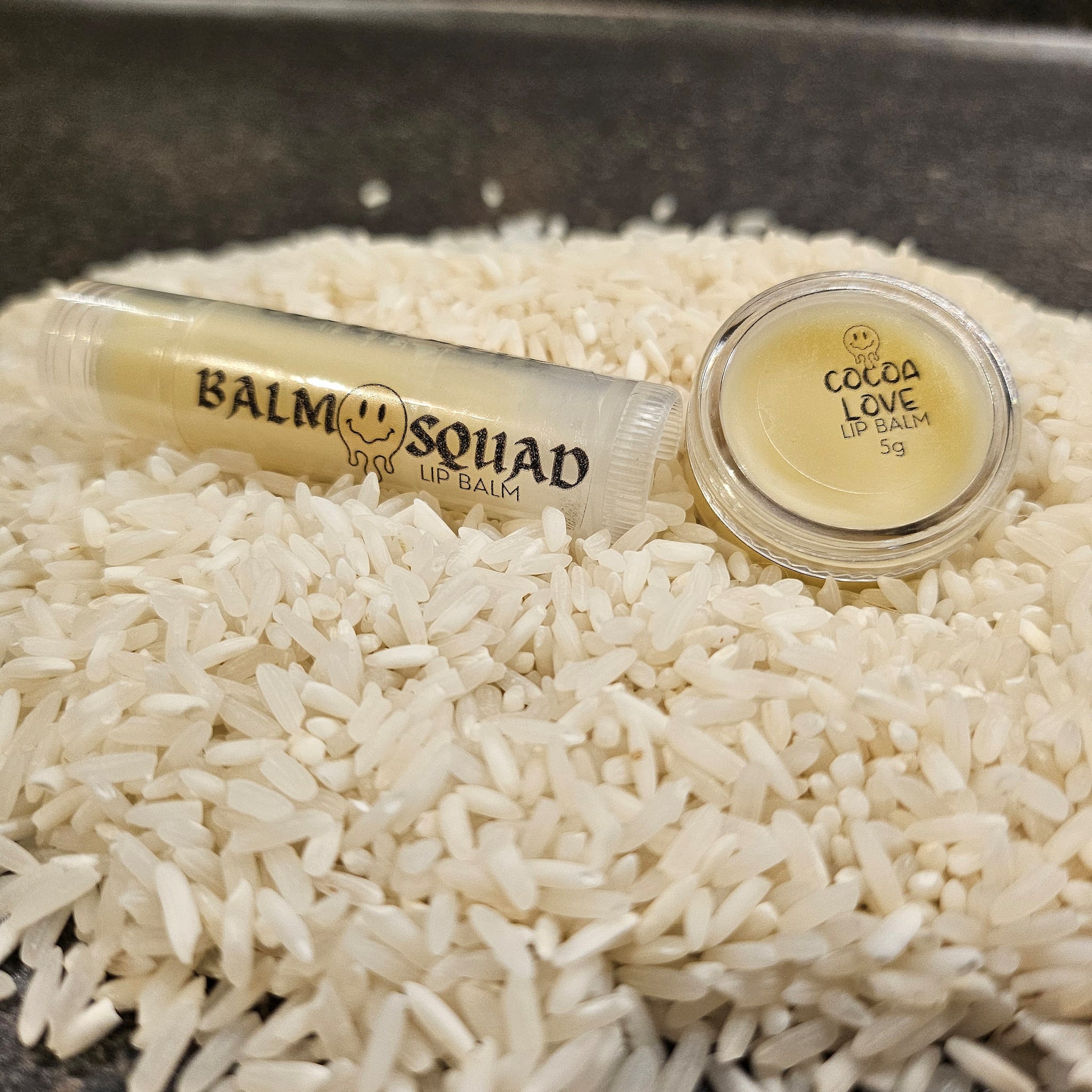 Lip balm tubes and container, yellow balm, clear tube, white rice background, Balm Squad brand