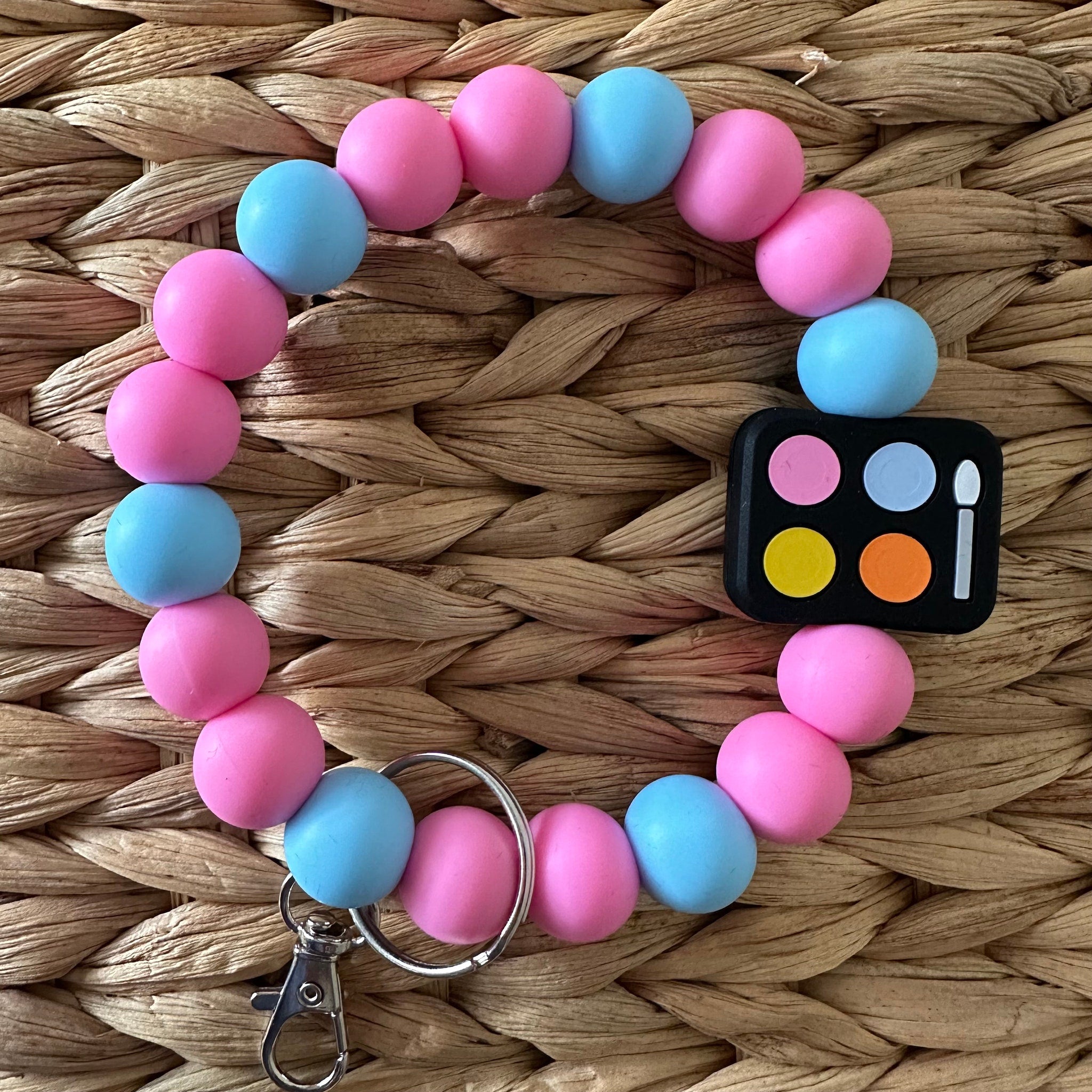 Side view of mini eyeshadow palette keychain with six vibrant shades in a sleek black compact