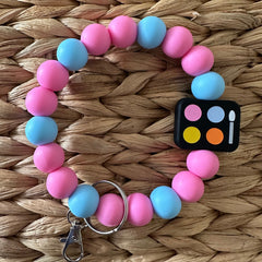 Side view of mini eyeshadow palette keychain with six vibrant shades in a sleek black compact