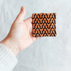 Square patterned fabric in orange and black held in hand, geometric design, textile material