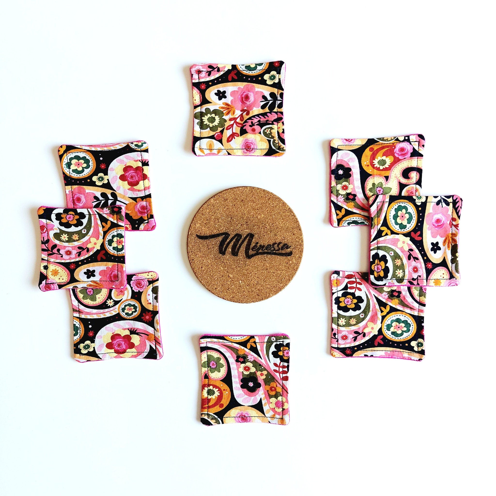 Coasters with floral pattern, black background, pink trim, and Miresse brand name on cork coaster
