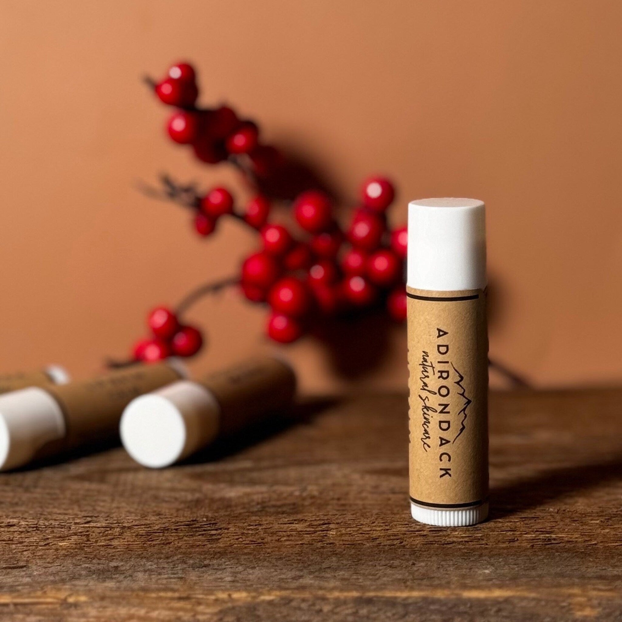 Lip balm tube with white cap, brown paper label, and Adirondack Natural Skincare text