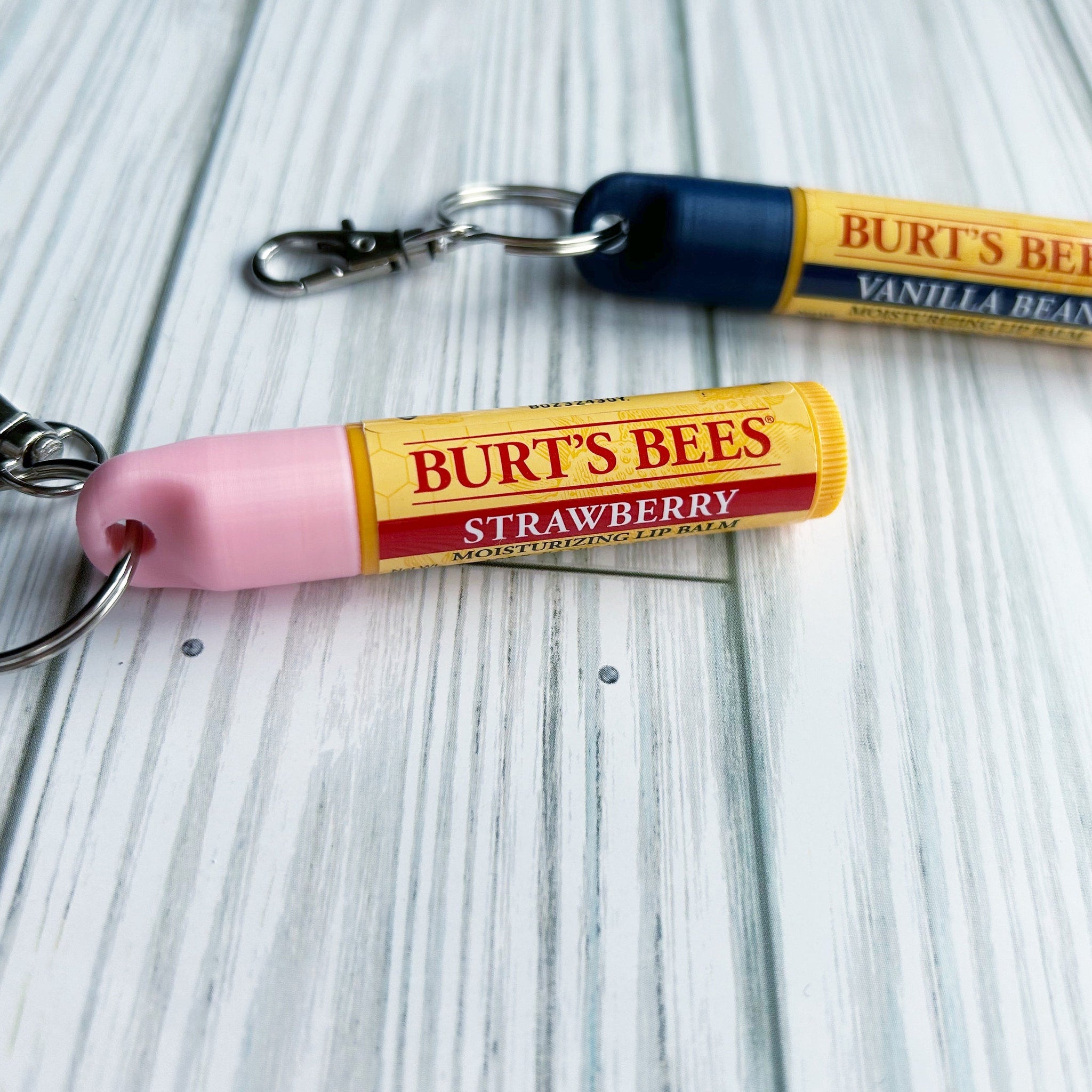 Lip balm tubes with pink, yellow, and blue accents, Burt's Bees branding, attached to keychains