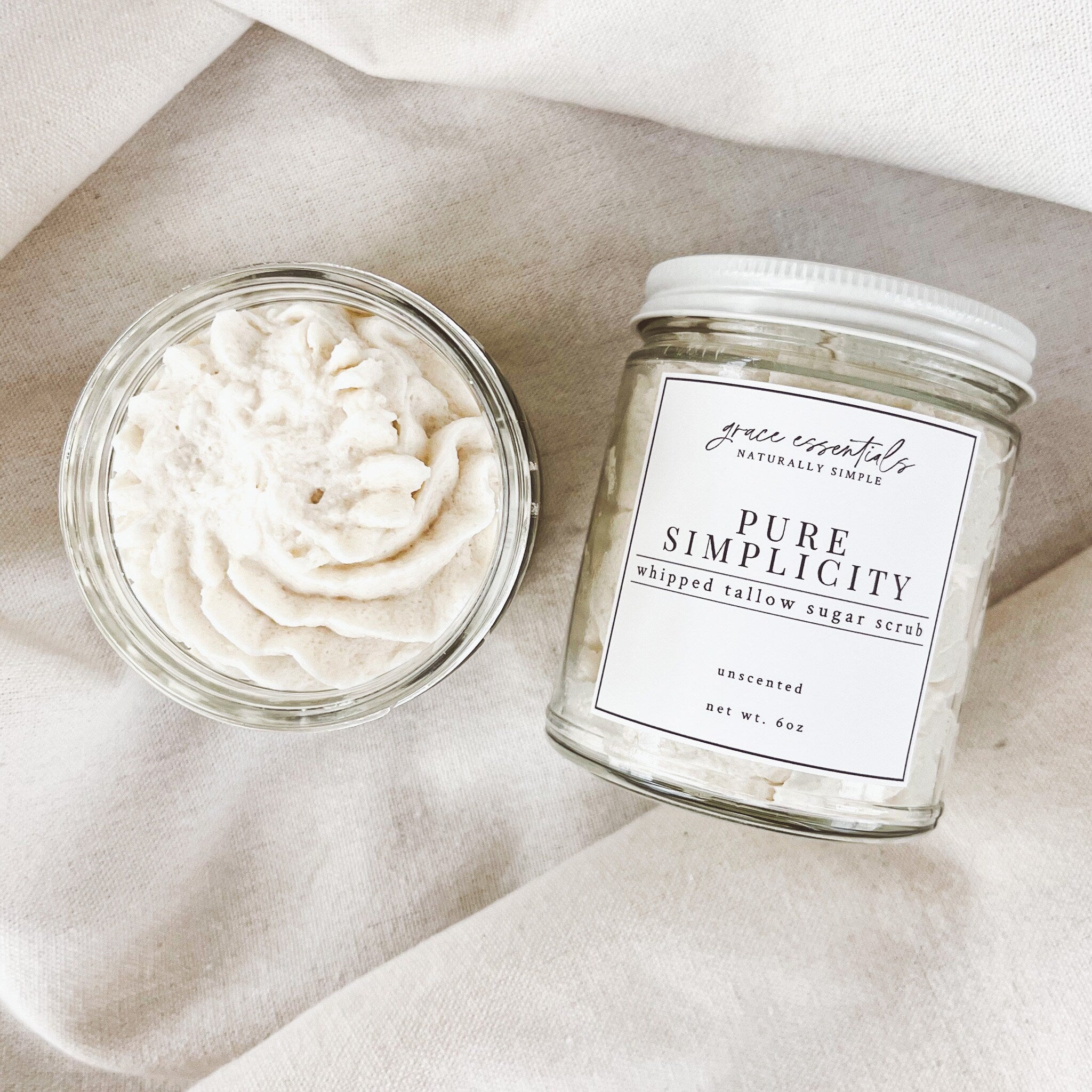 Whipped tallow sugar scrub with white cream, glass jar, and PURE SIMPLICITY label on linen