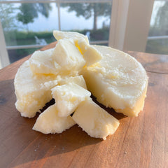 Butter chunks on a wooden cutting board, with white and yellow tones, rough texture, and natural light.