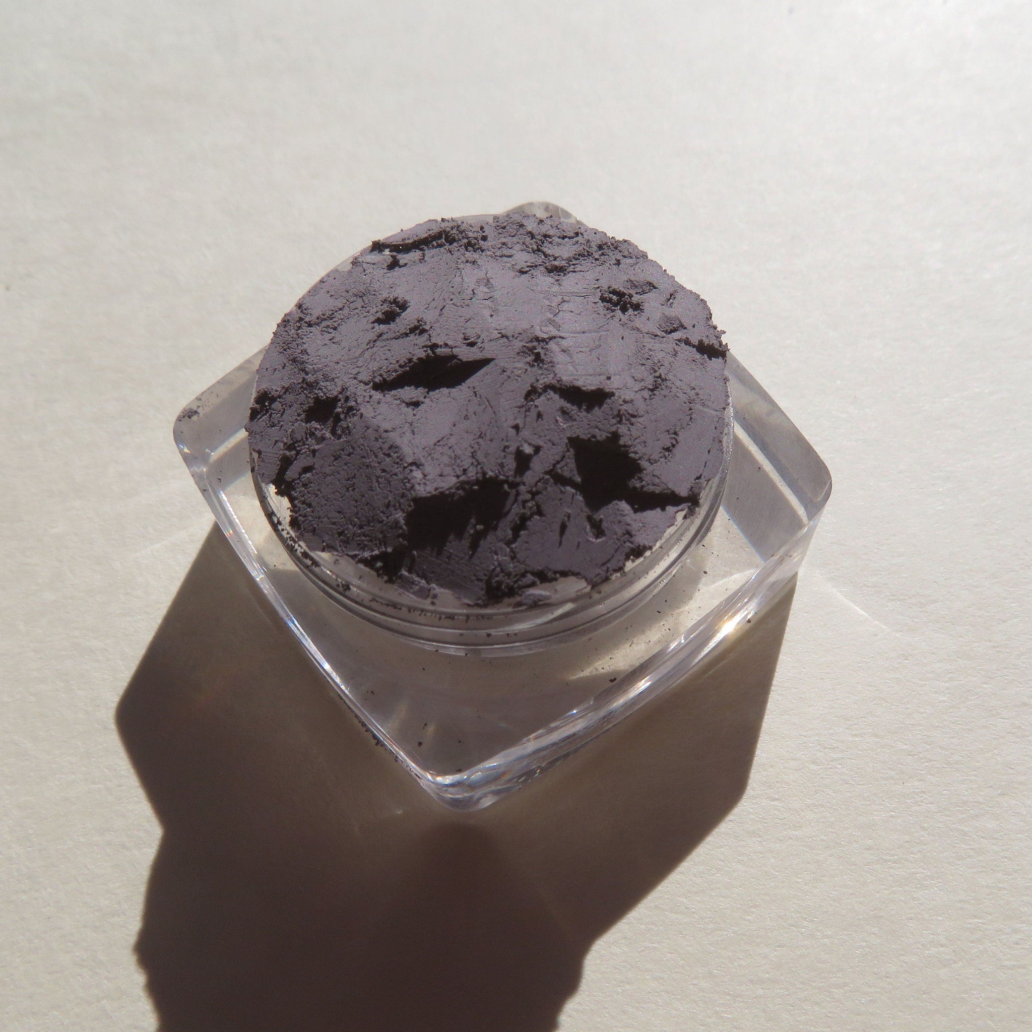 Powdered makeup, dark gray, textured, in clear square container