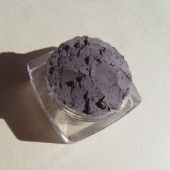 Powdered eyeshadow in gray, textured, in a clear plastic container