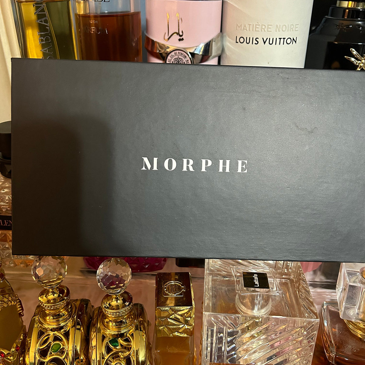 Open Morphe eyeshadow palette displaying 12 vibrant matte and shimmer shades in a sleek black case