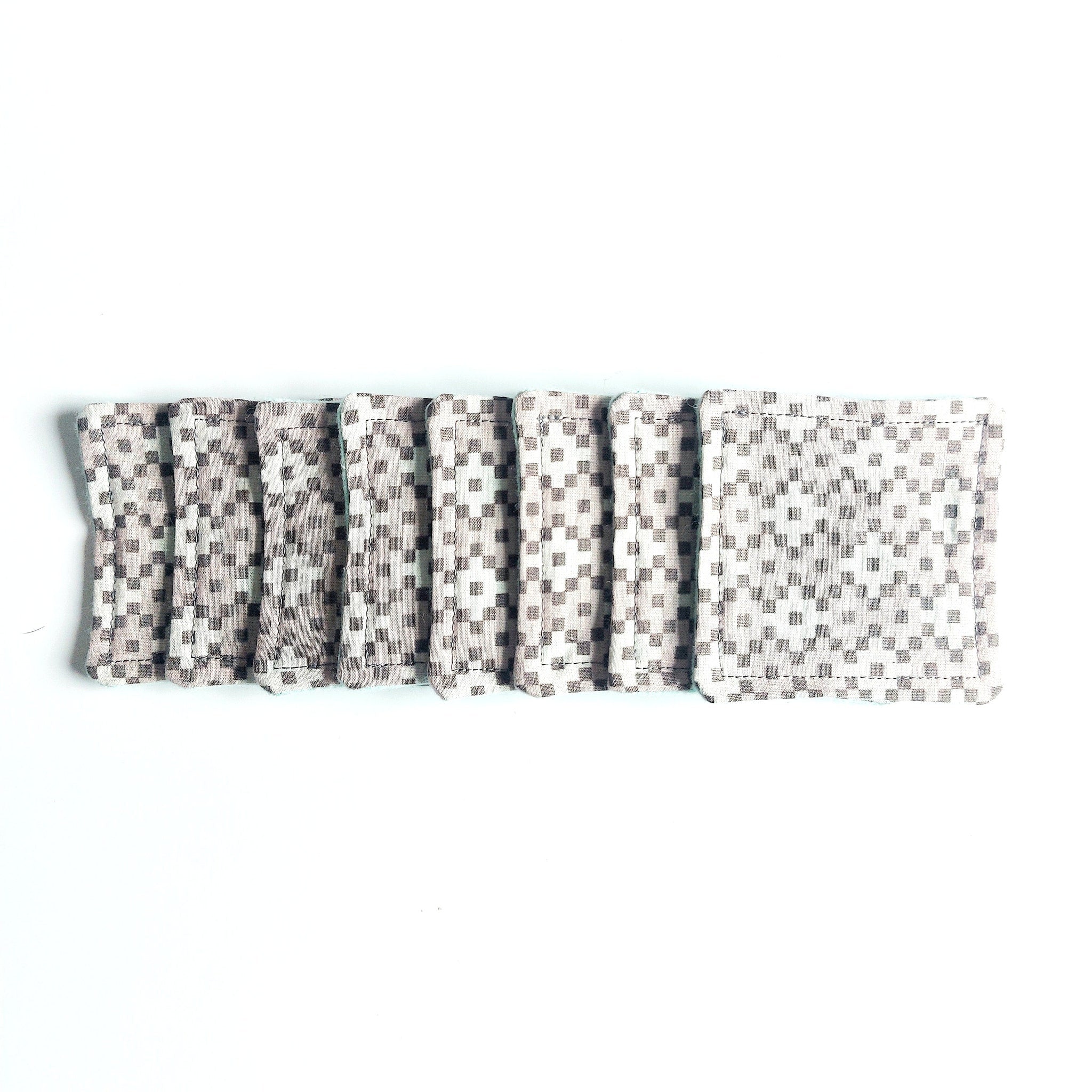 Coasters with gray and white checkered pattern, stitched edges, stacked on white surface