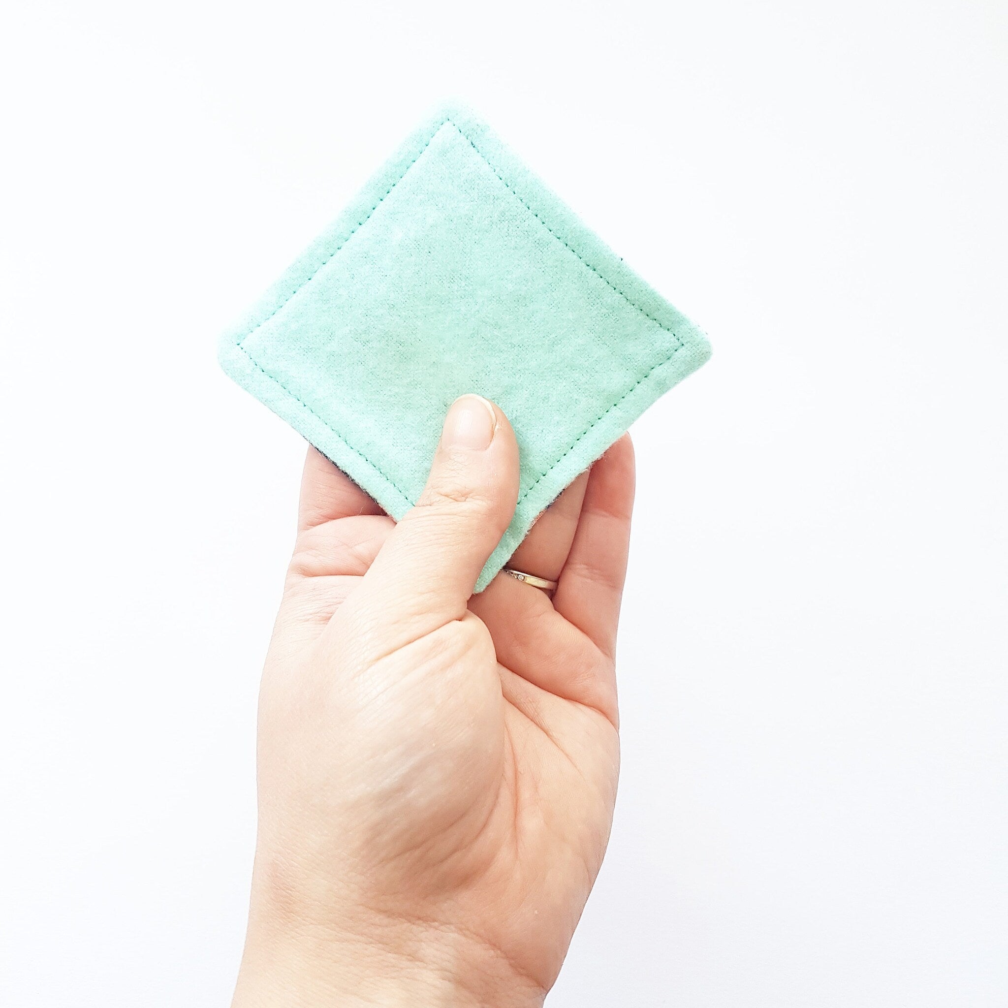 Reusable face pad, mint green square, soft material, held in hand