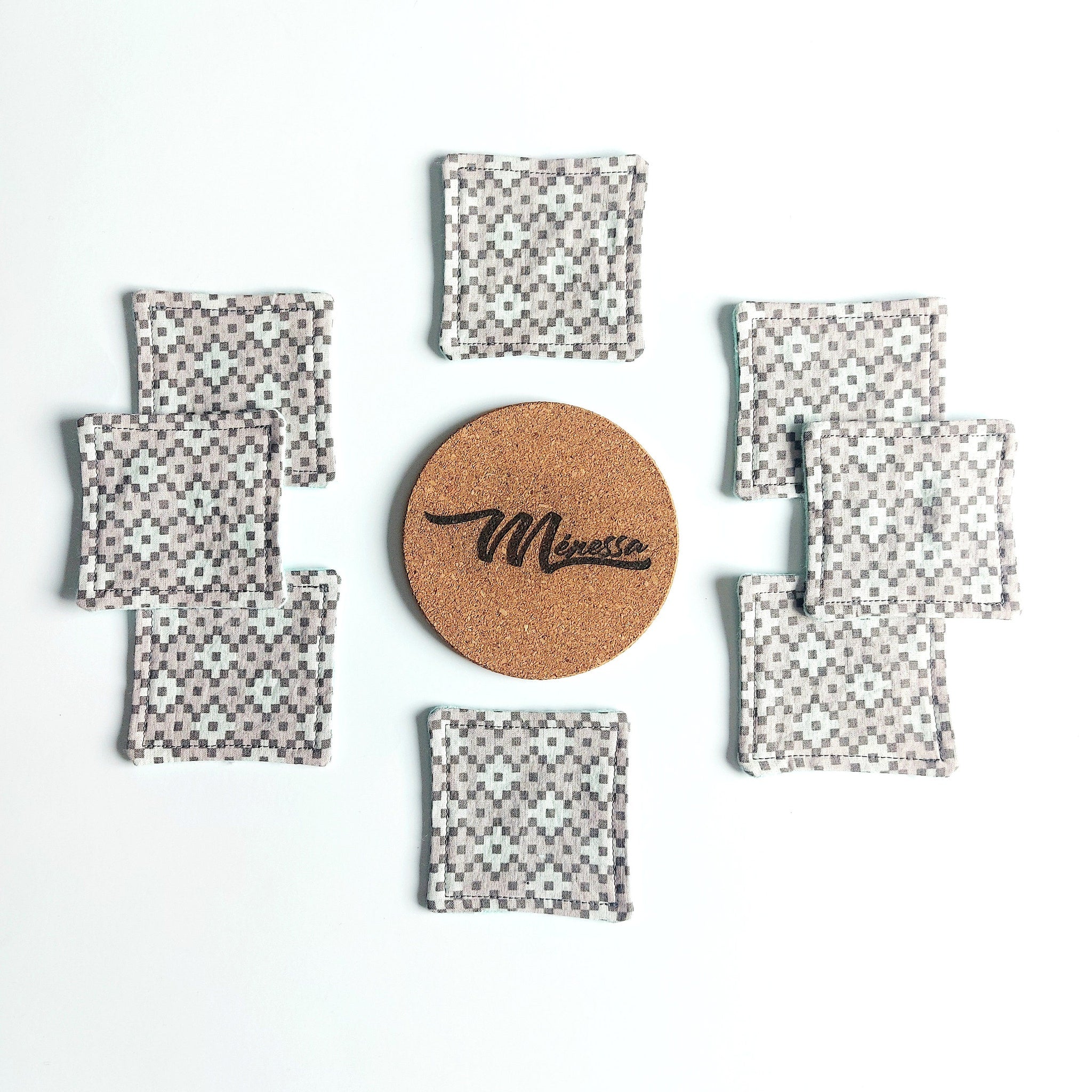 Coasters with gray and white checkered pattern and cork center with Meressa text
