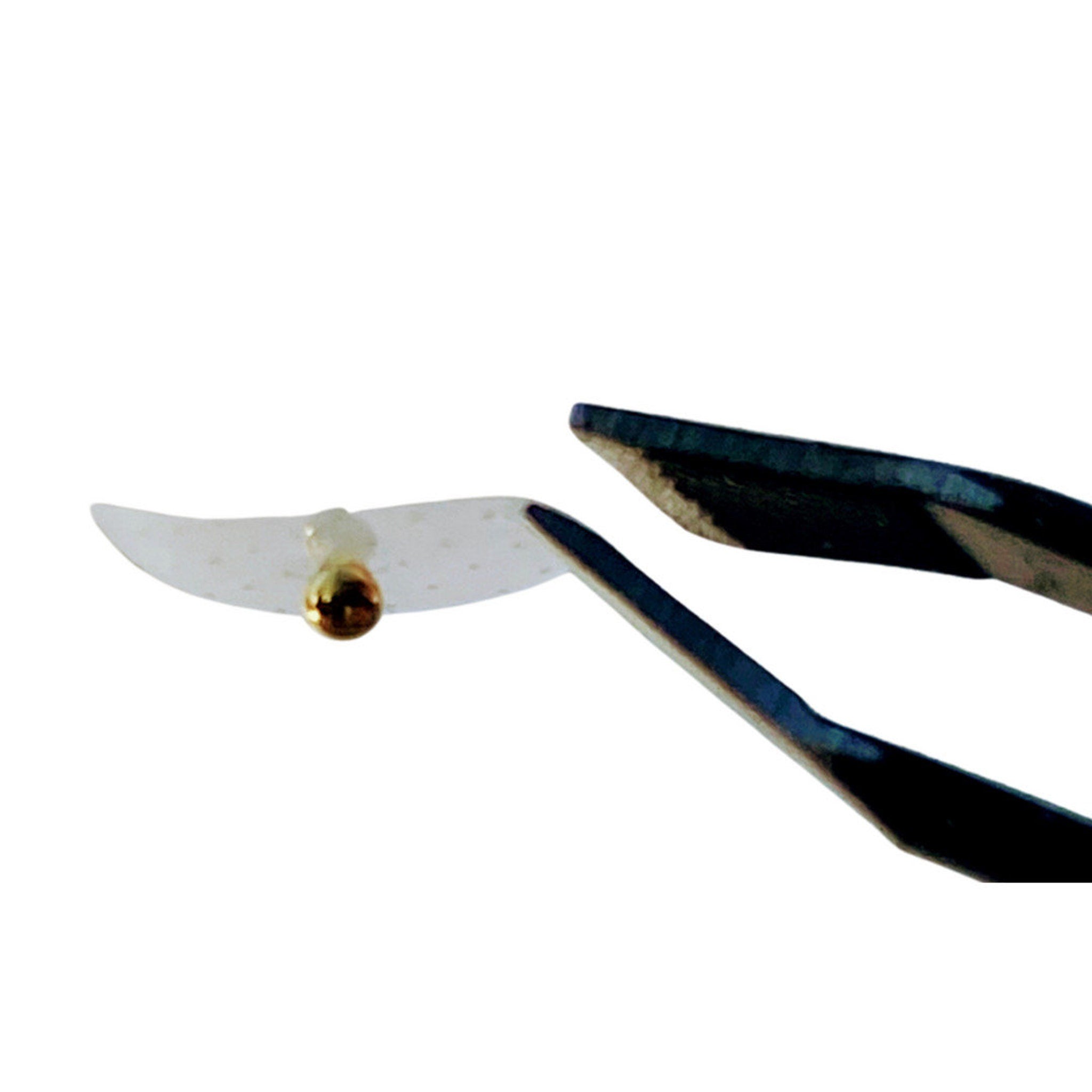 Tweezers holding a clear, perforated material with a gold bead, dark metal tool