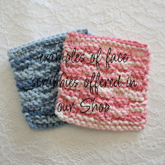Face scrubbies in blue and pink knit with white accents, shown on lace fabric