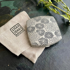 Powder compact with floral pattern, Lisa Jenks for Origins, on linen pouch