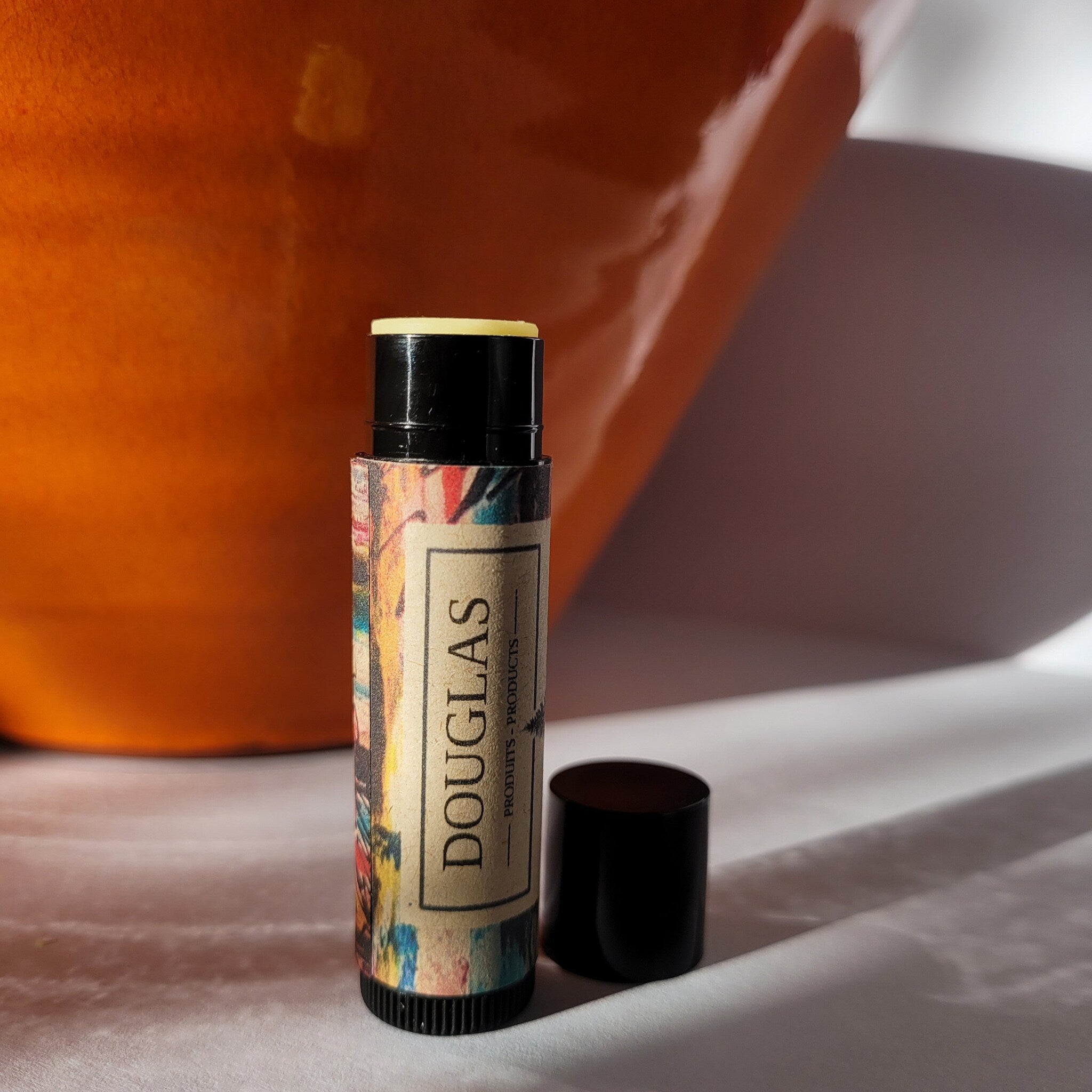 Lip balm with black cap, patterned paper, and visible DOUGLAS branding