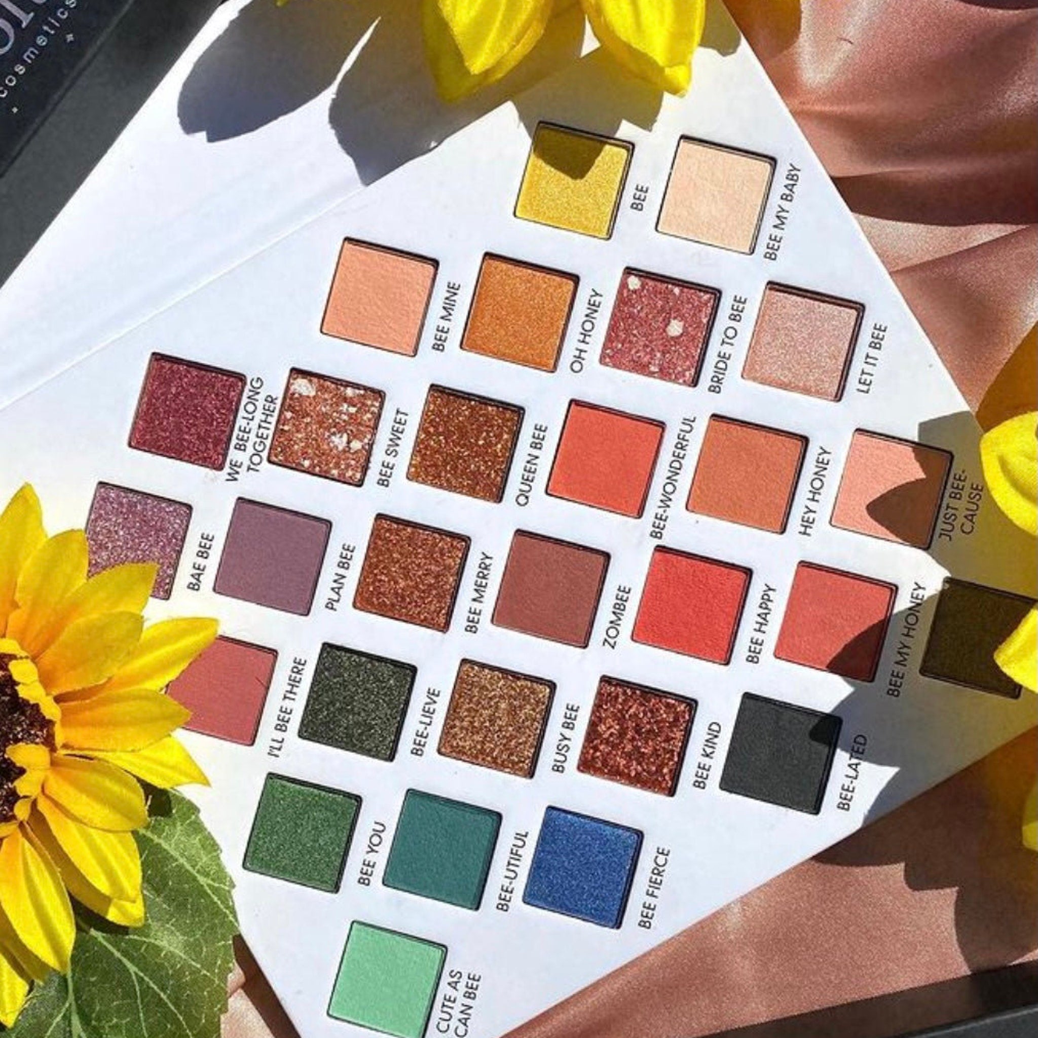 Eyeshadow palette with various colors, square pans, and brand text on each pan