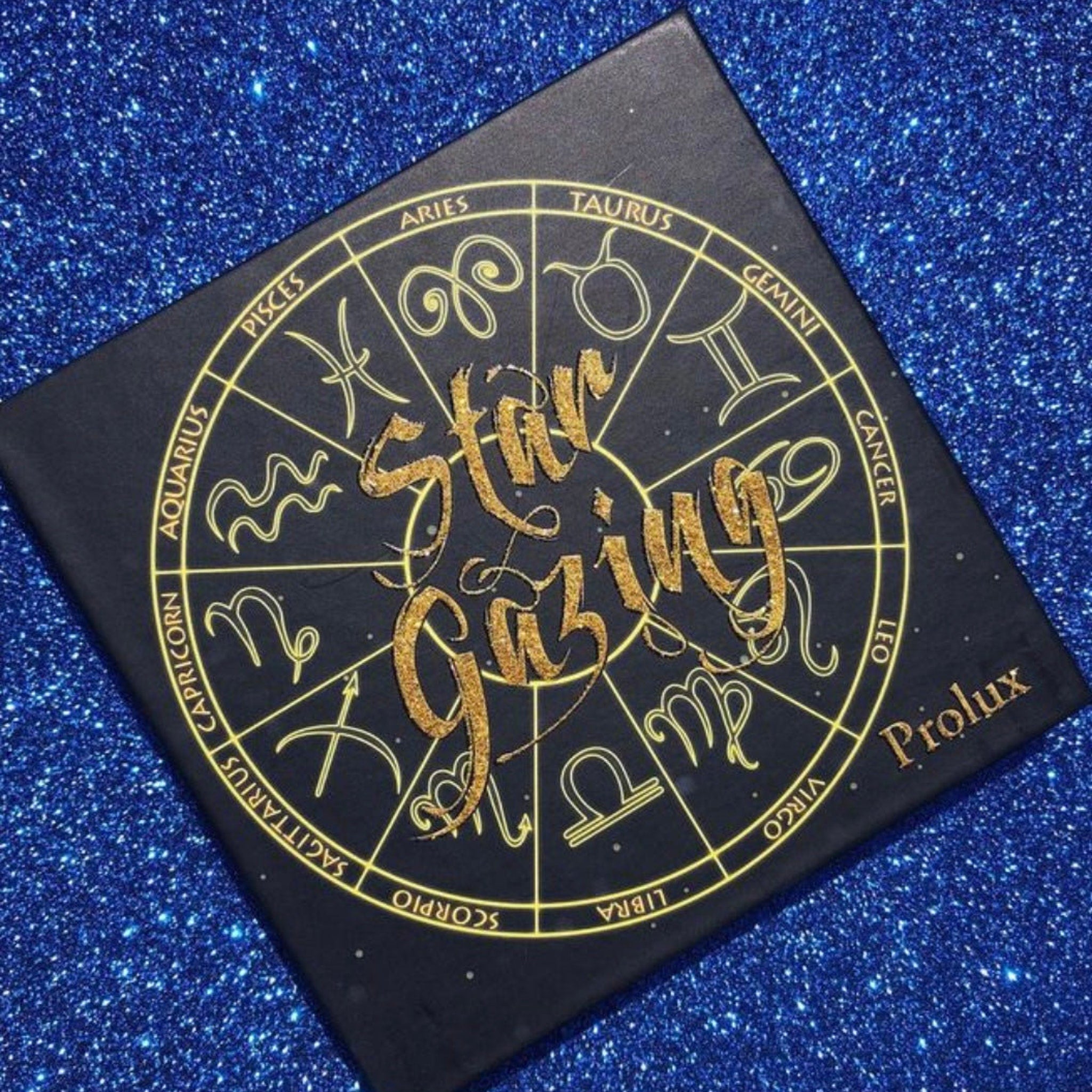 Makeup palette with black base, gold lettering and zodiac symbols, Prolux brand name visible