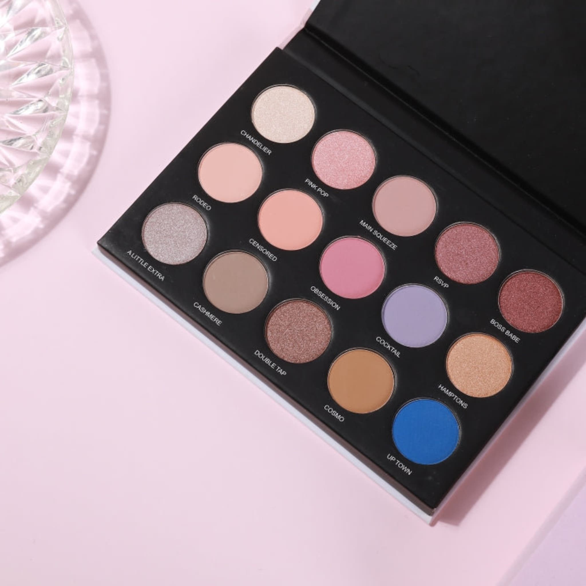 Eyeshadow palette with multiple colors including pink, brown, and blue, in a black compact case