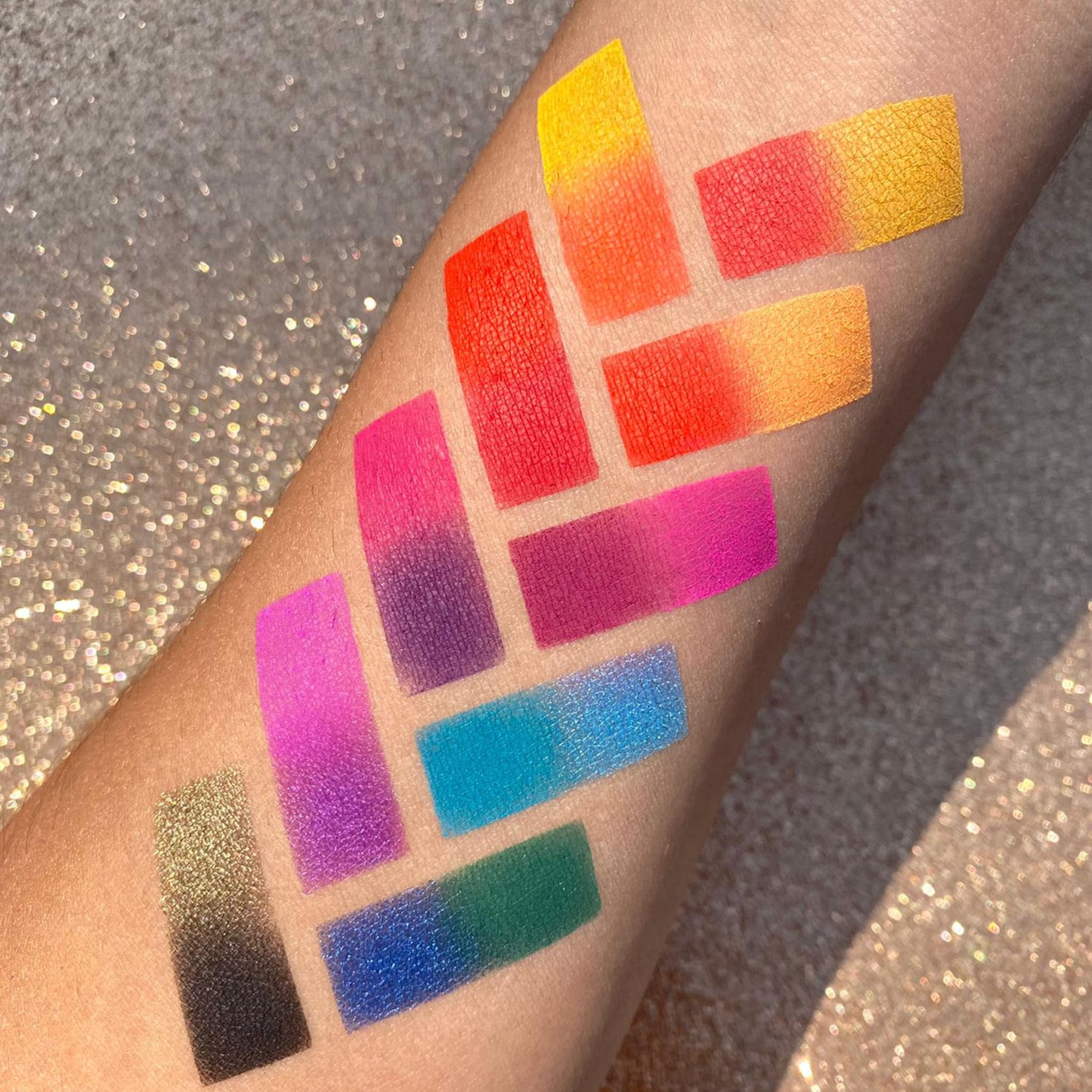 Eyeshadow swatches in various bright colors, textured application on skin, with gradient effect