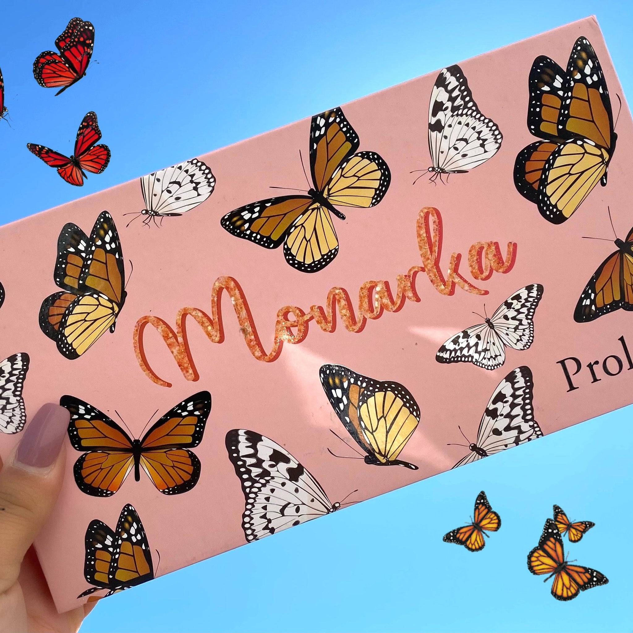 Pink box with Monarcha text, orange butterflies, and blue sky background