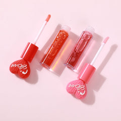 Close-up of a hand applying shimmery pink lip gloss with a doe-foot applicator on lips