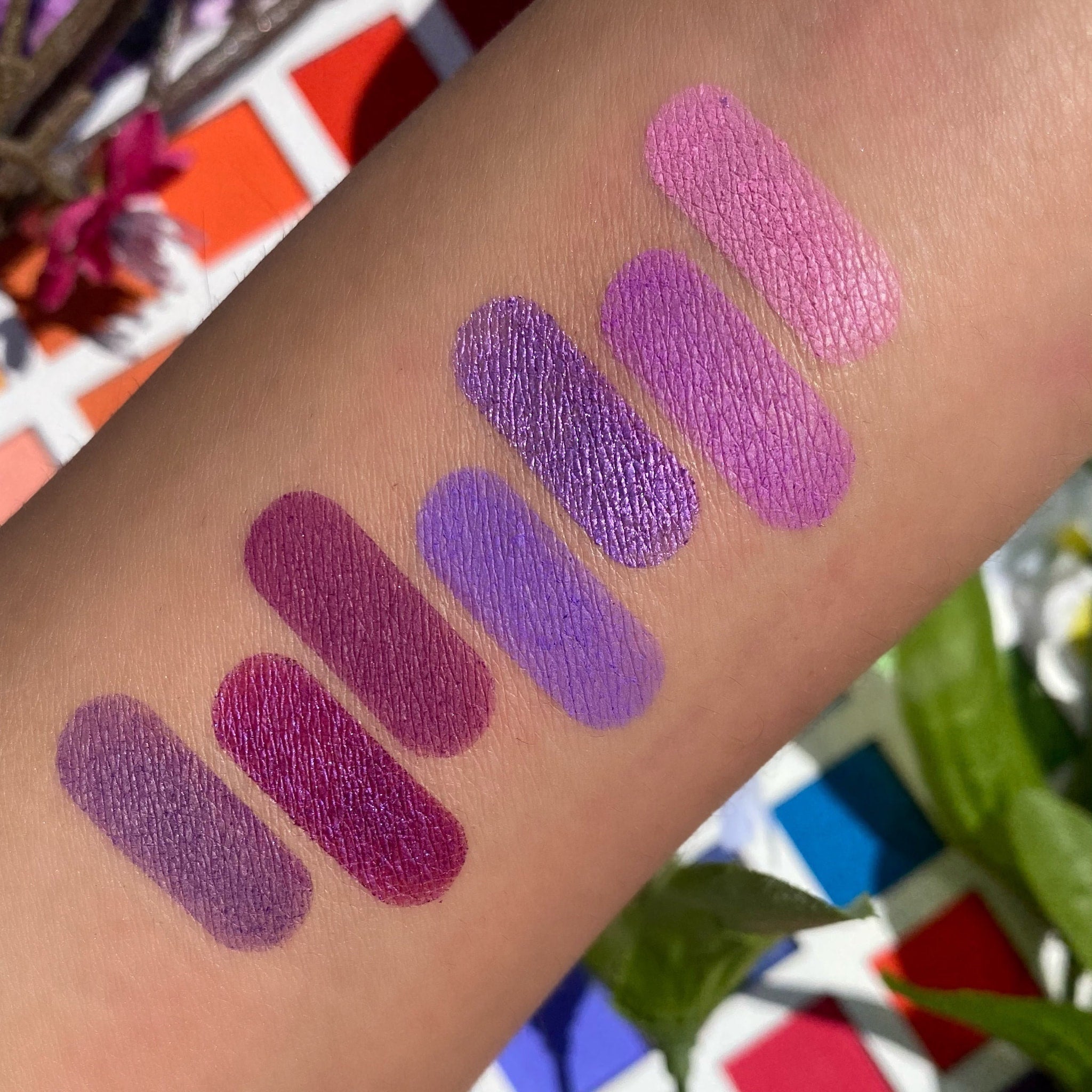 Eyeshadow swatches in purple shades, matte and metallic finishes, applied on skin for color test