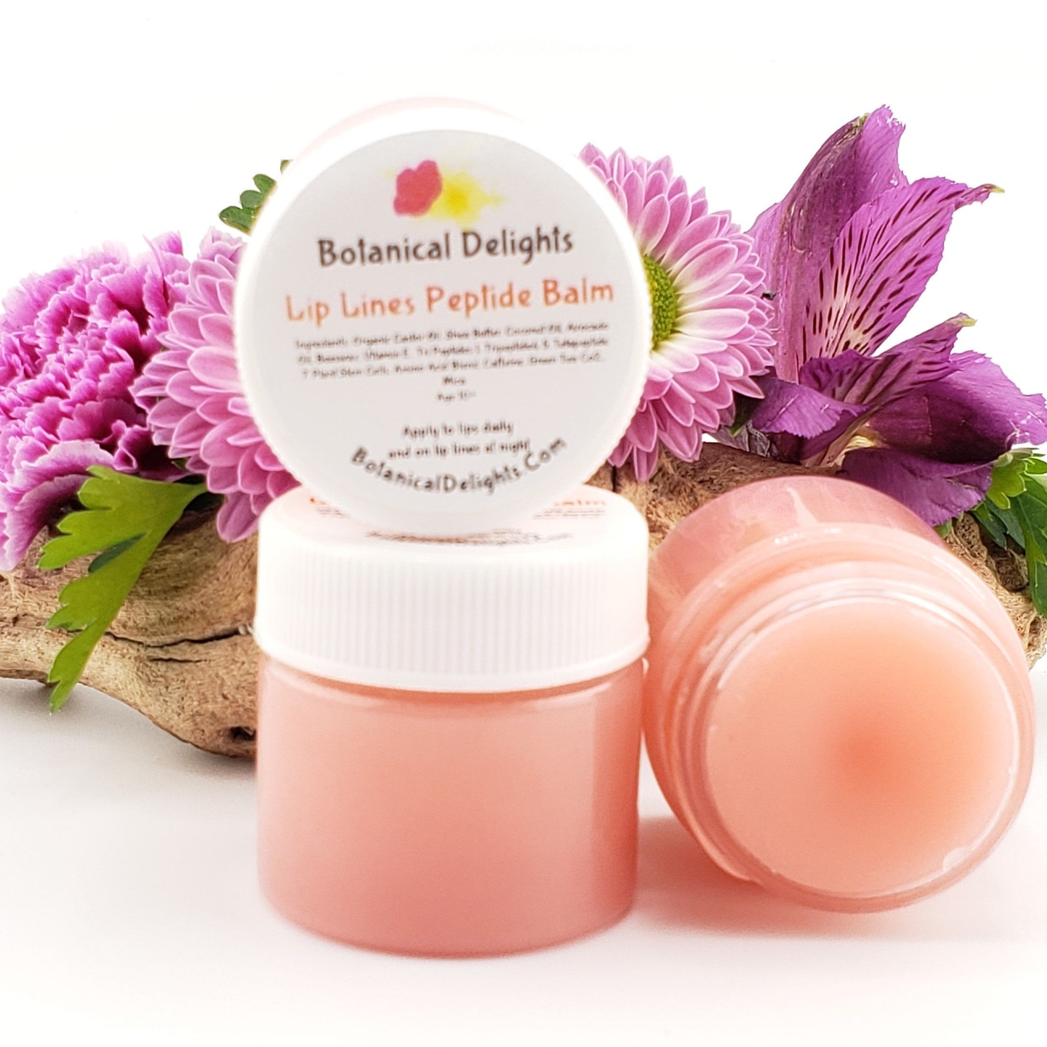 Lip balm jars with pink contents, white lids, and Botanical Delights label, displayed with flowers and wood