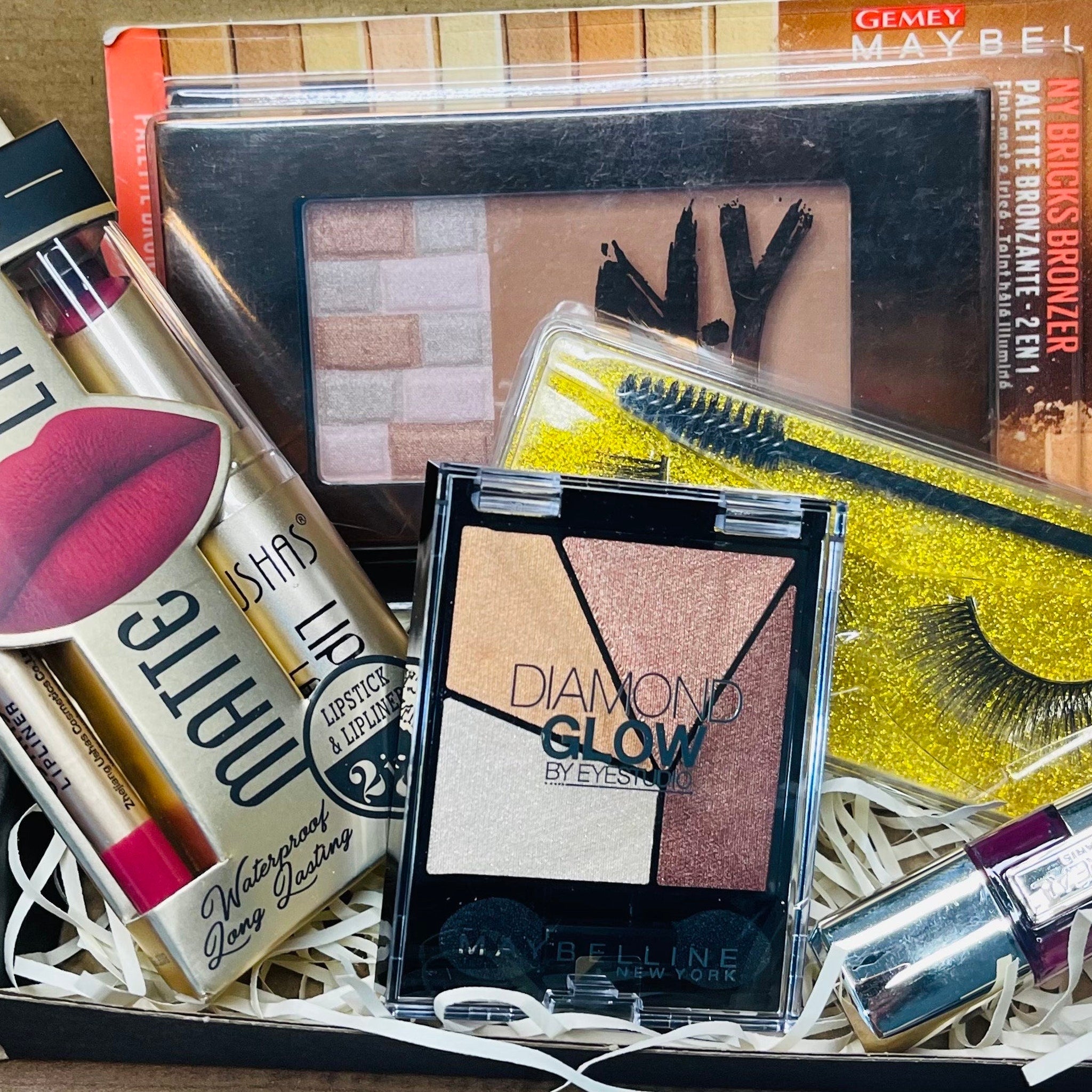 Side view of surprise beauty box showcasing assorted shimmering eye shadow pans in vibrant hues