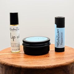 Lip oil and scrub set with black containers, BalmTree branding, and wooden surface