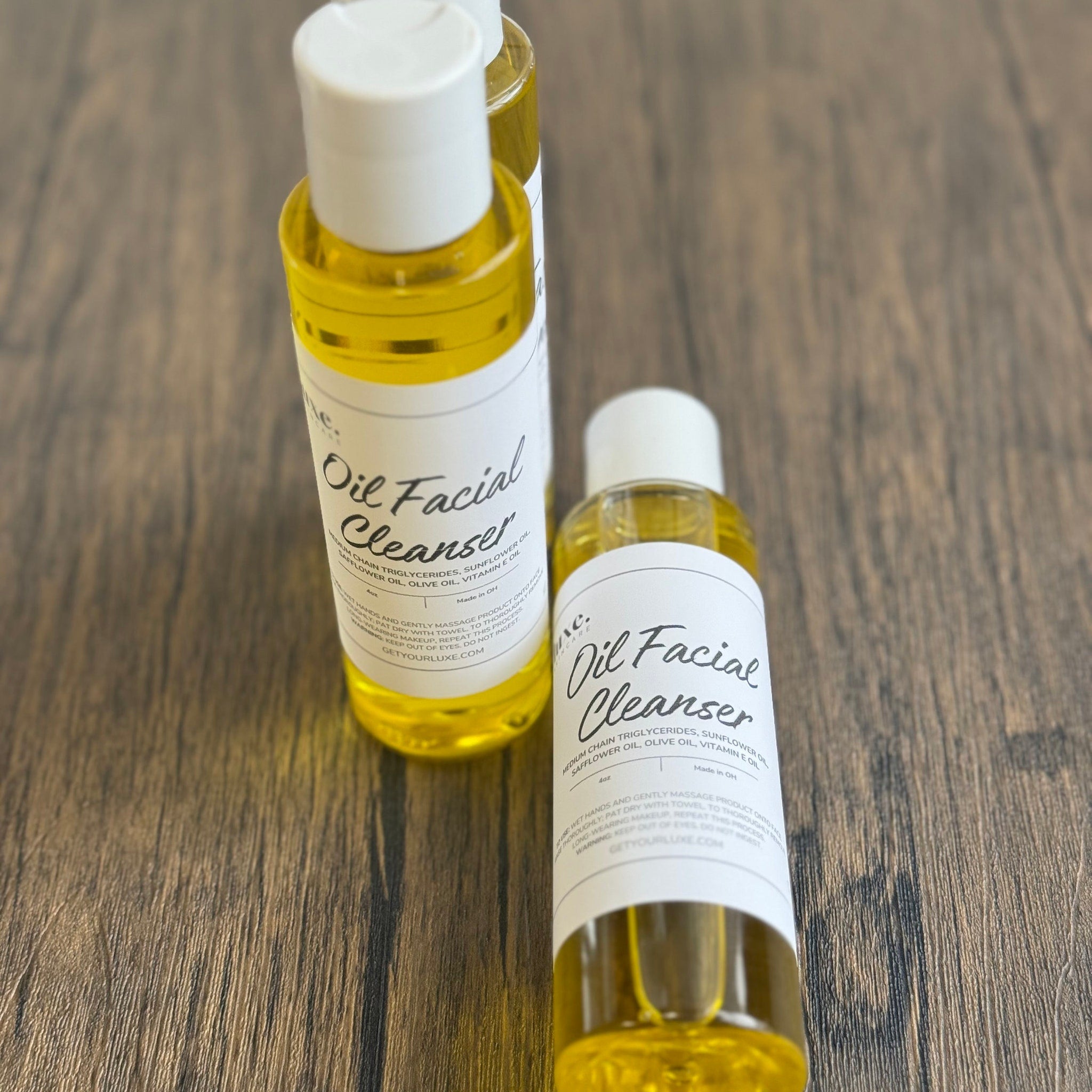 Oil facial cleanser bottles, yellow liquid, white labels, on wood surface