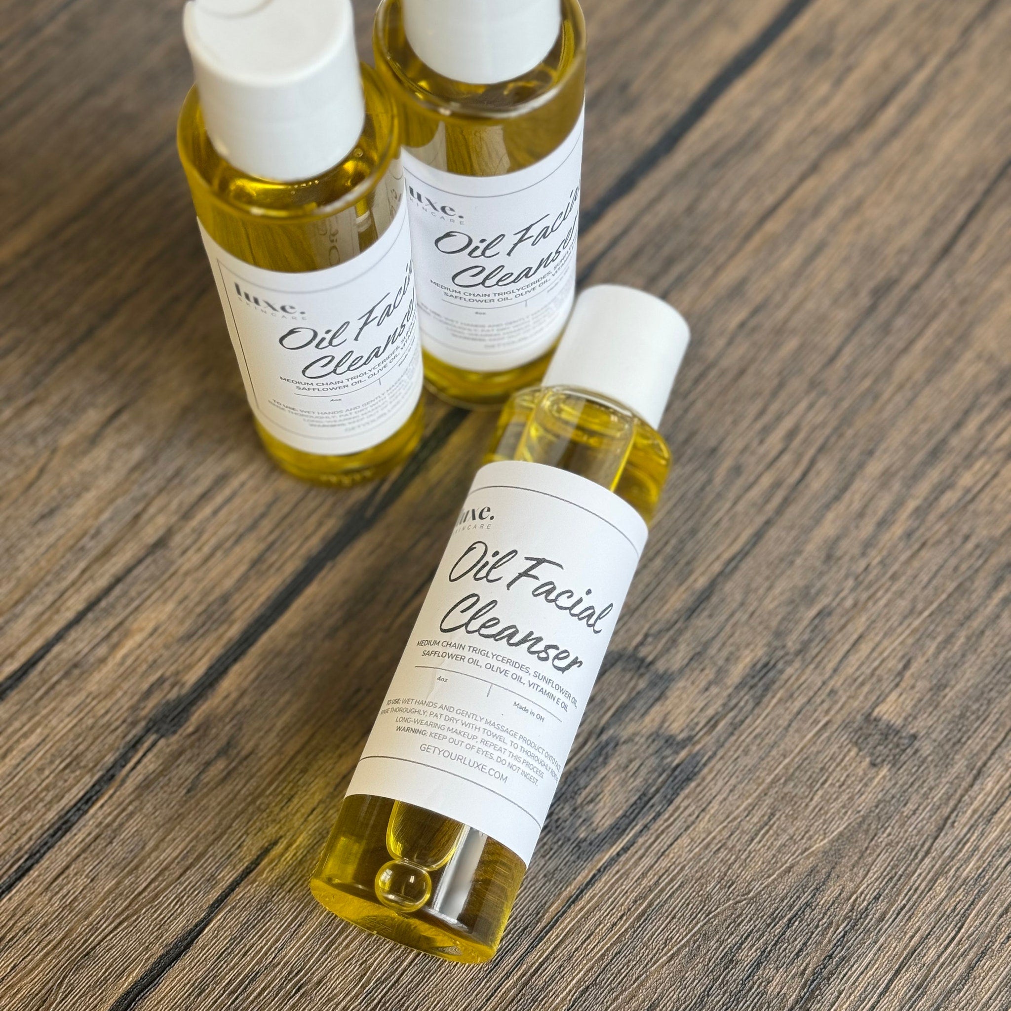 Oil facial cleanser bottles, yellow liquid, white label, on wood surface