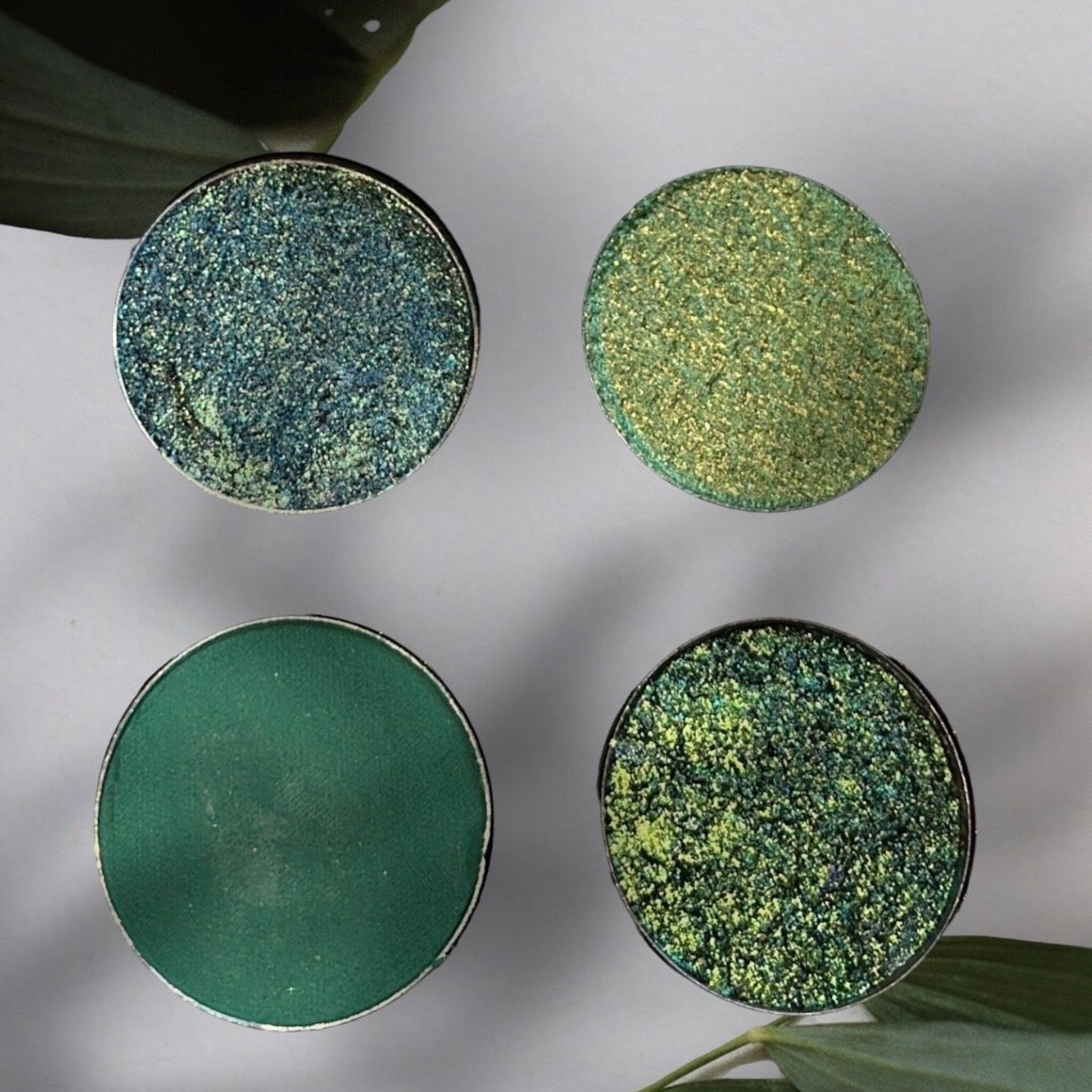 Hand applying lush green eyeshadow with a blending brush, showcasing smooth pigment and shimmer finish