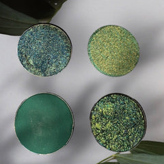 Hand applying lush green eyeshadow with a blending brush, showcasing smooth pigment and shimmer finish