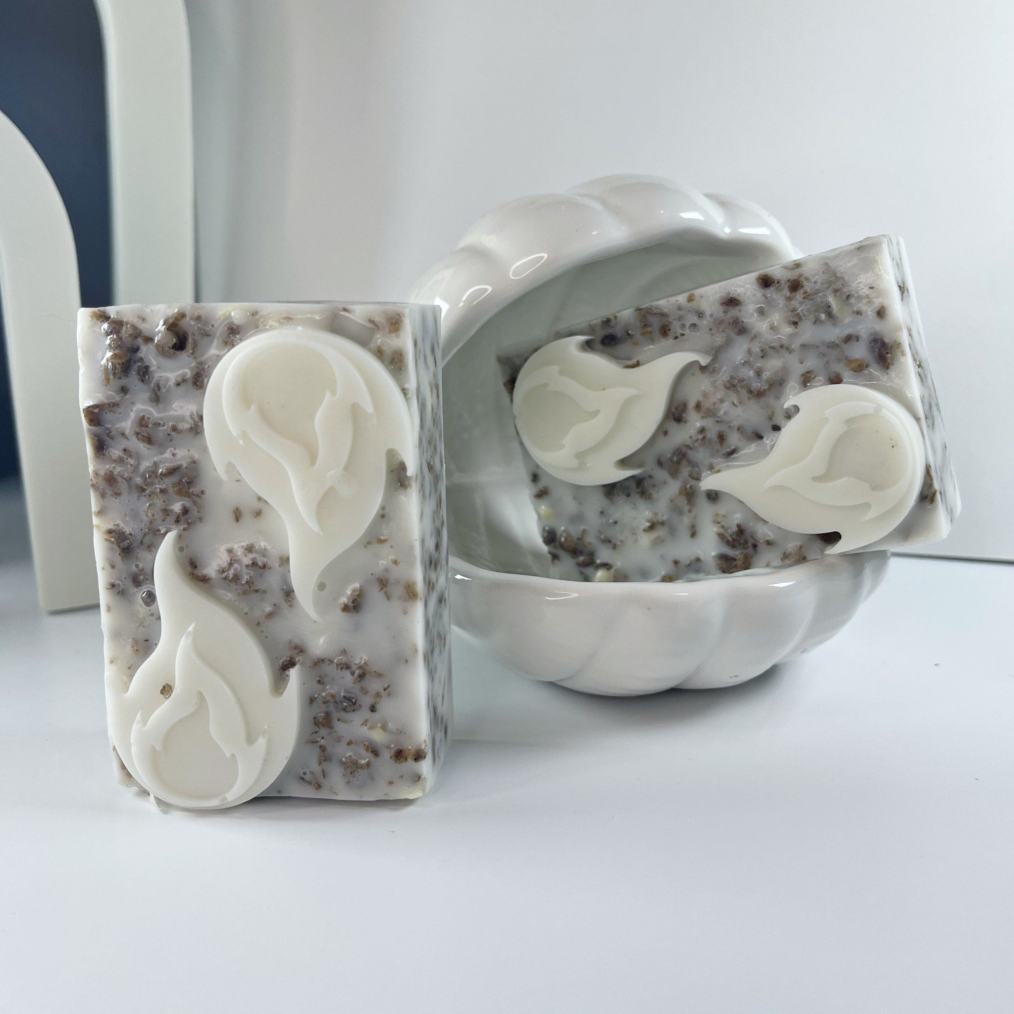 Soap bars with white floral accents, speckled pattern, and ceramic dish display