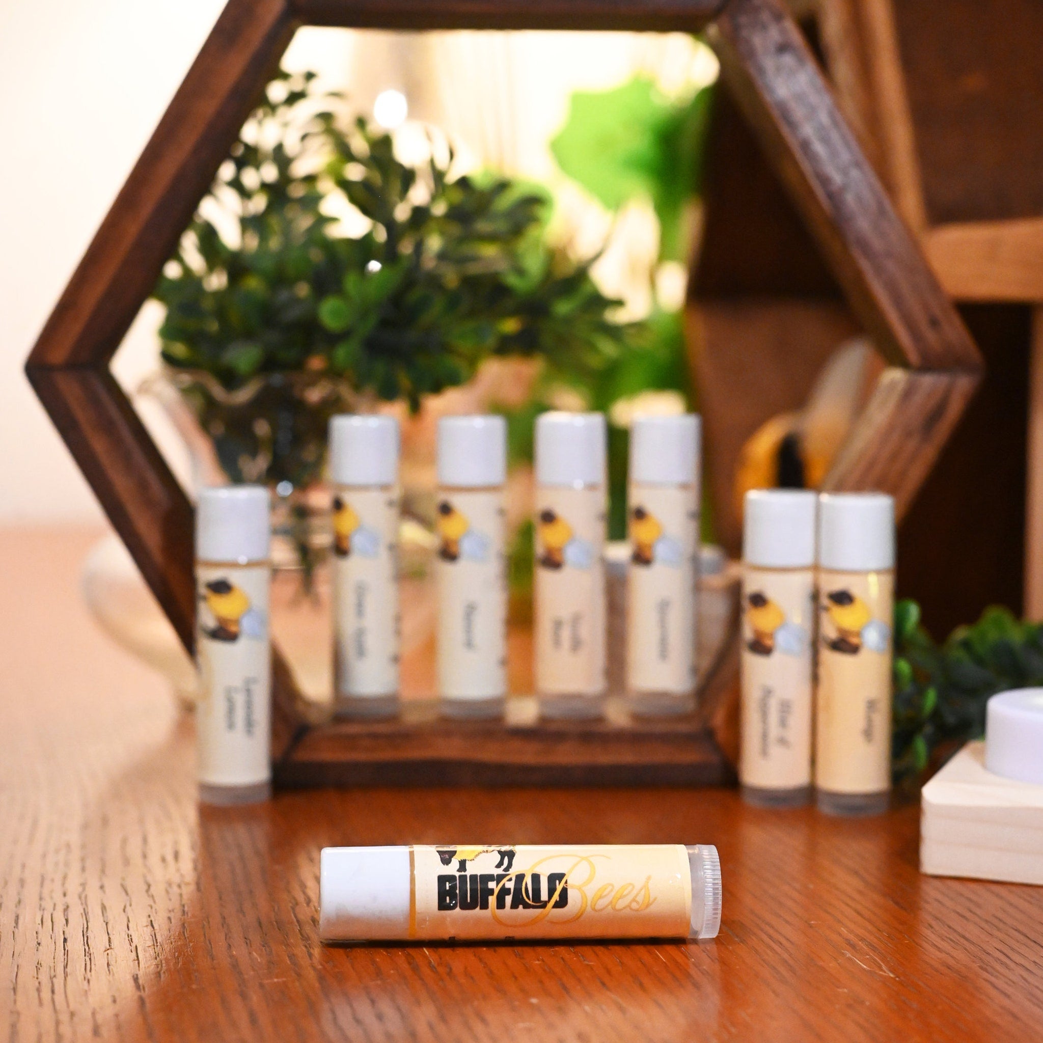 Lip balm tubes with white caps and Buffalo Bees label on wooden table display