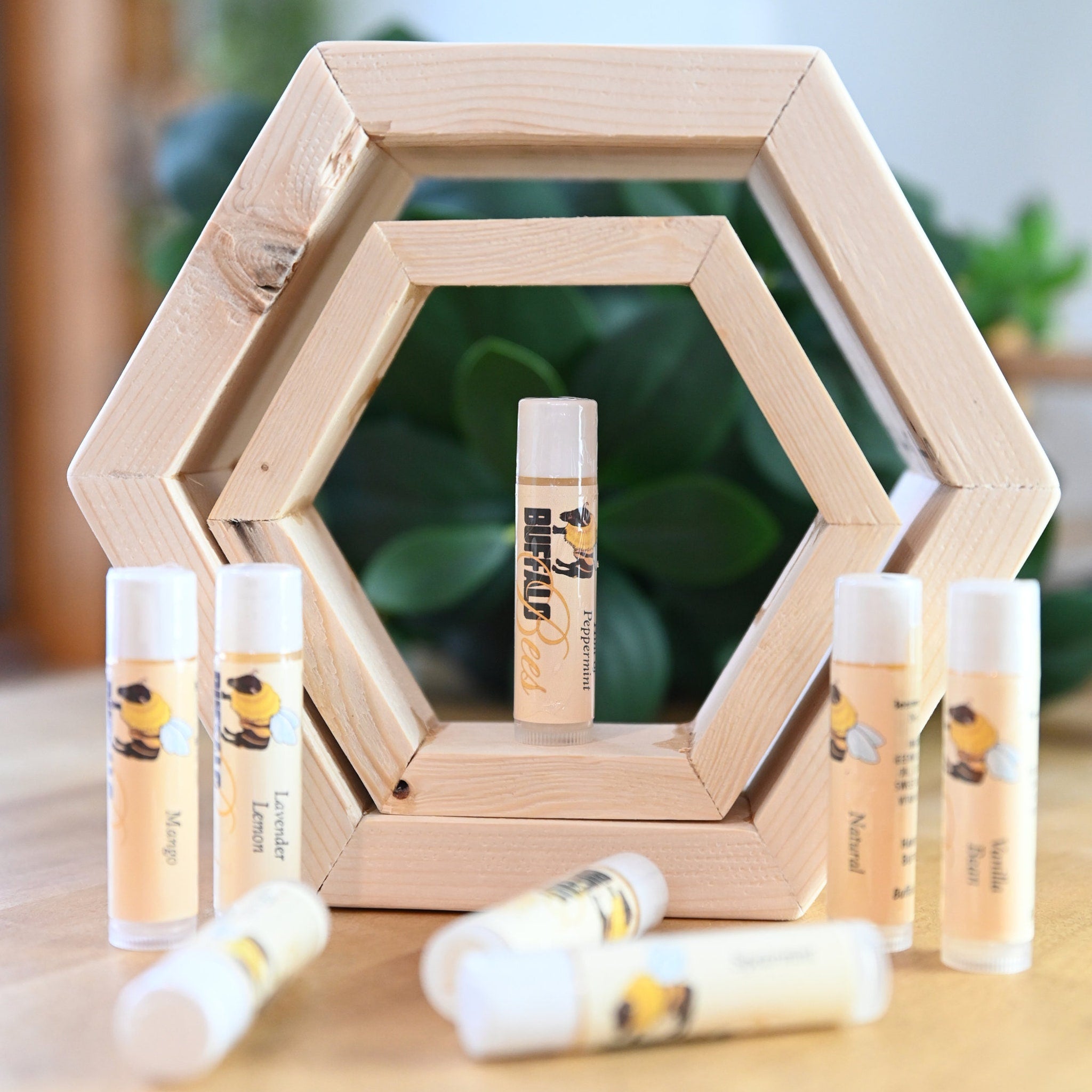 Lip balm tubes with white caps and labels, displayed on wooden hexagon frame, Buffalo Bees brand