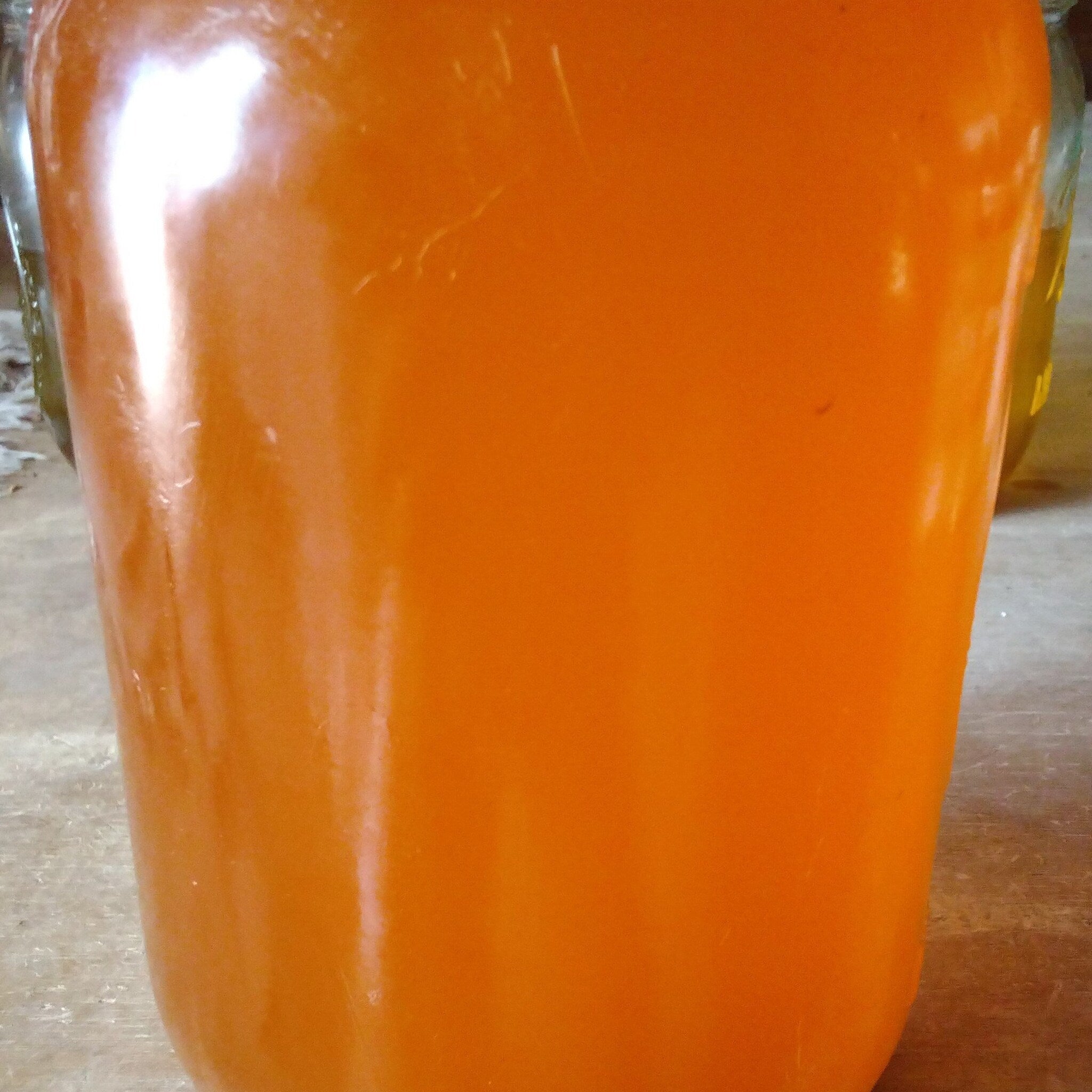 Orange liquid in a glass container, glossy surface, blurred background
