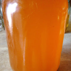 Orange liquid in a glass container, glossy surface, blurred background