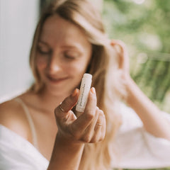 Lip balm tube, white plastic, Fraises Fraiches text, held in hand