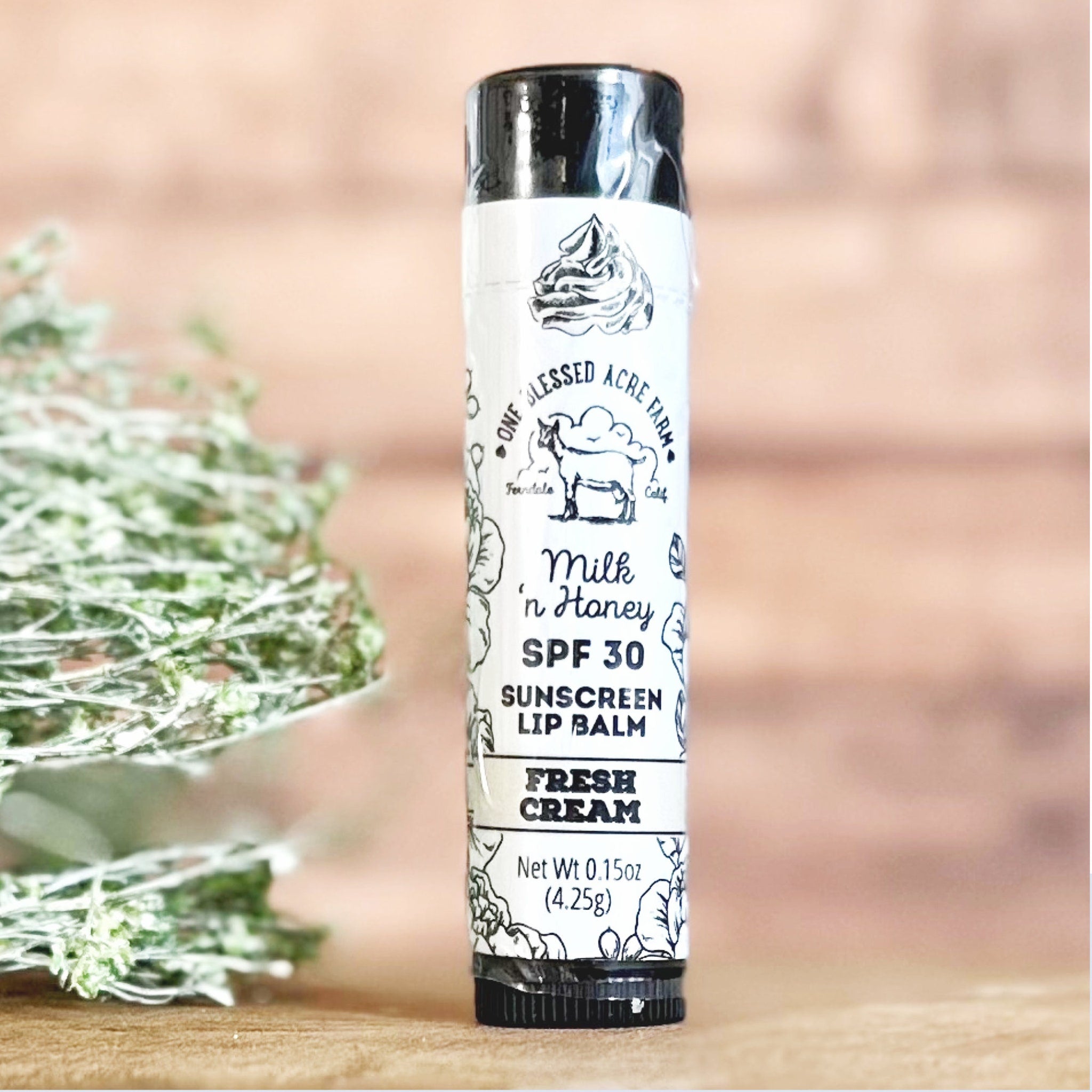 Sunscreen lip balm tube with white label, black text, and One Blessed Acre Farm branding