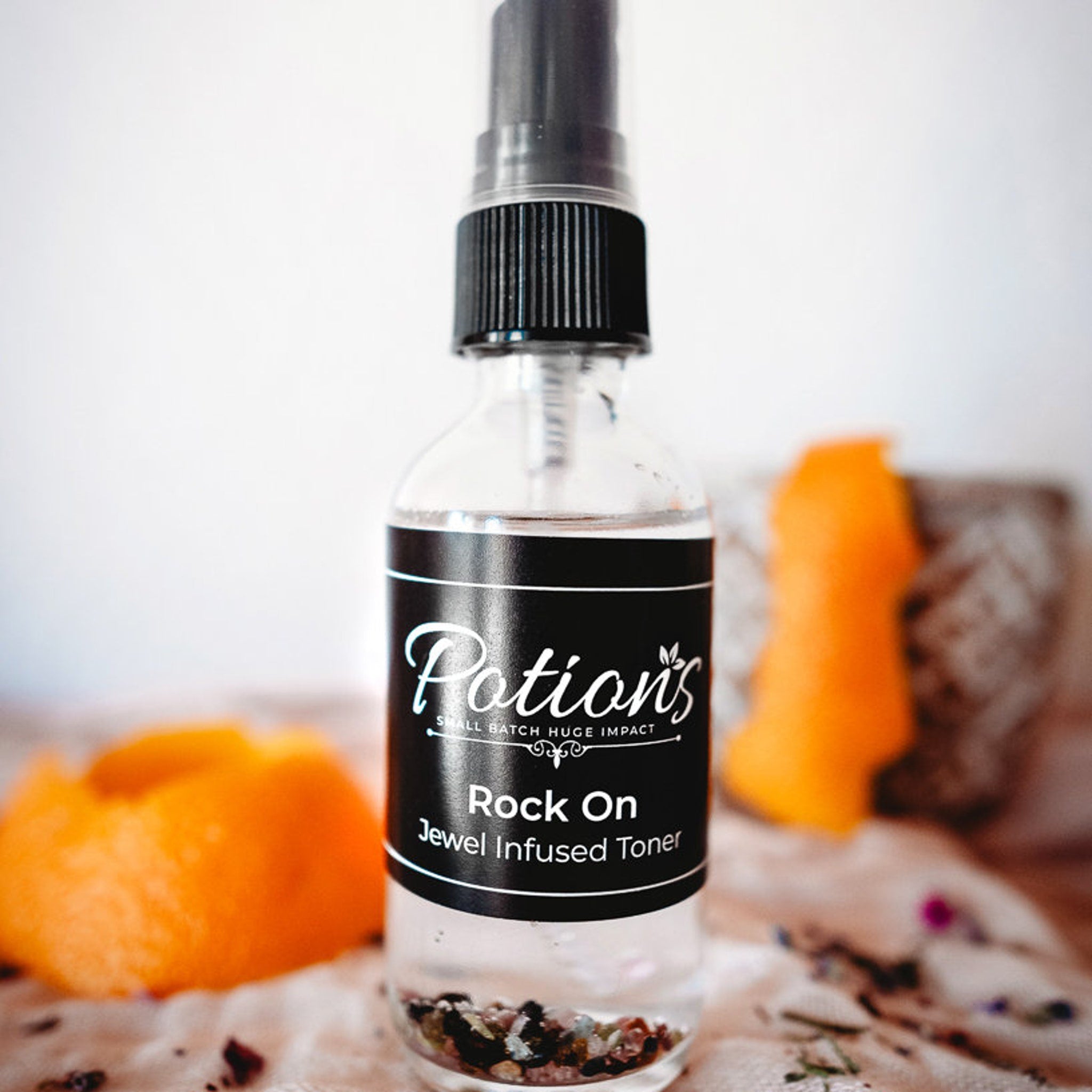 Toner bottle with black label, clear glass, and black spray top, by Potion's brand