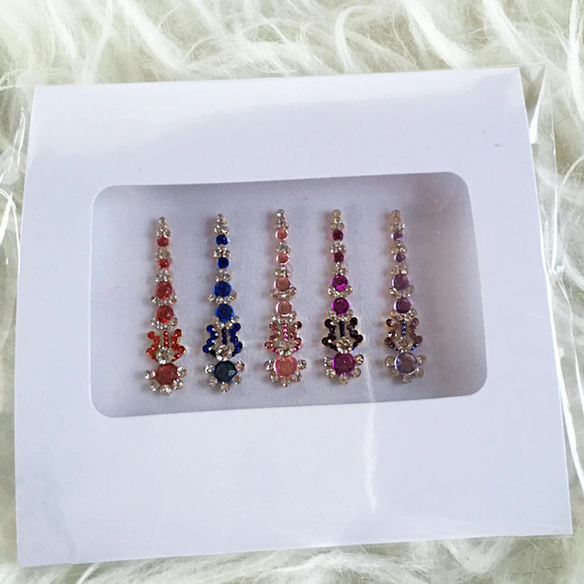 Jeweled body stickers in various colors, arranged in a row, with clear rhinestones and a vertical design