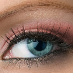 Close-up of fingers applying matte light pink vegan eyeshadow to eyelid with soft blending brush