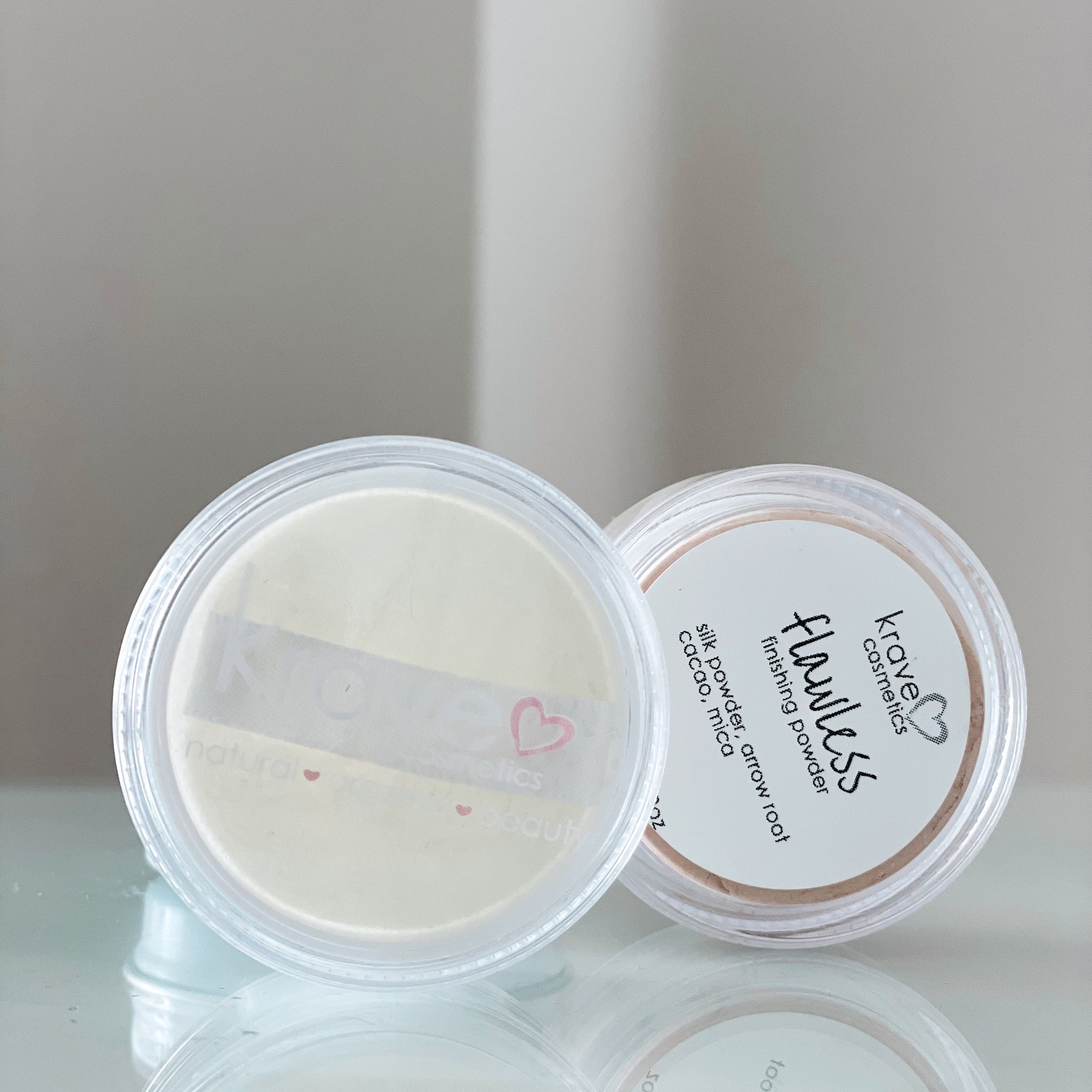 Finishing powder in clear plastic jars, "Krave Cosmetics" branding visible, light beige powder inside