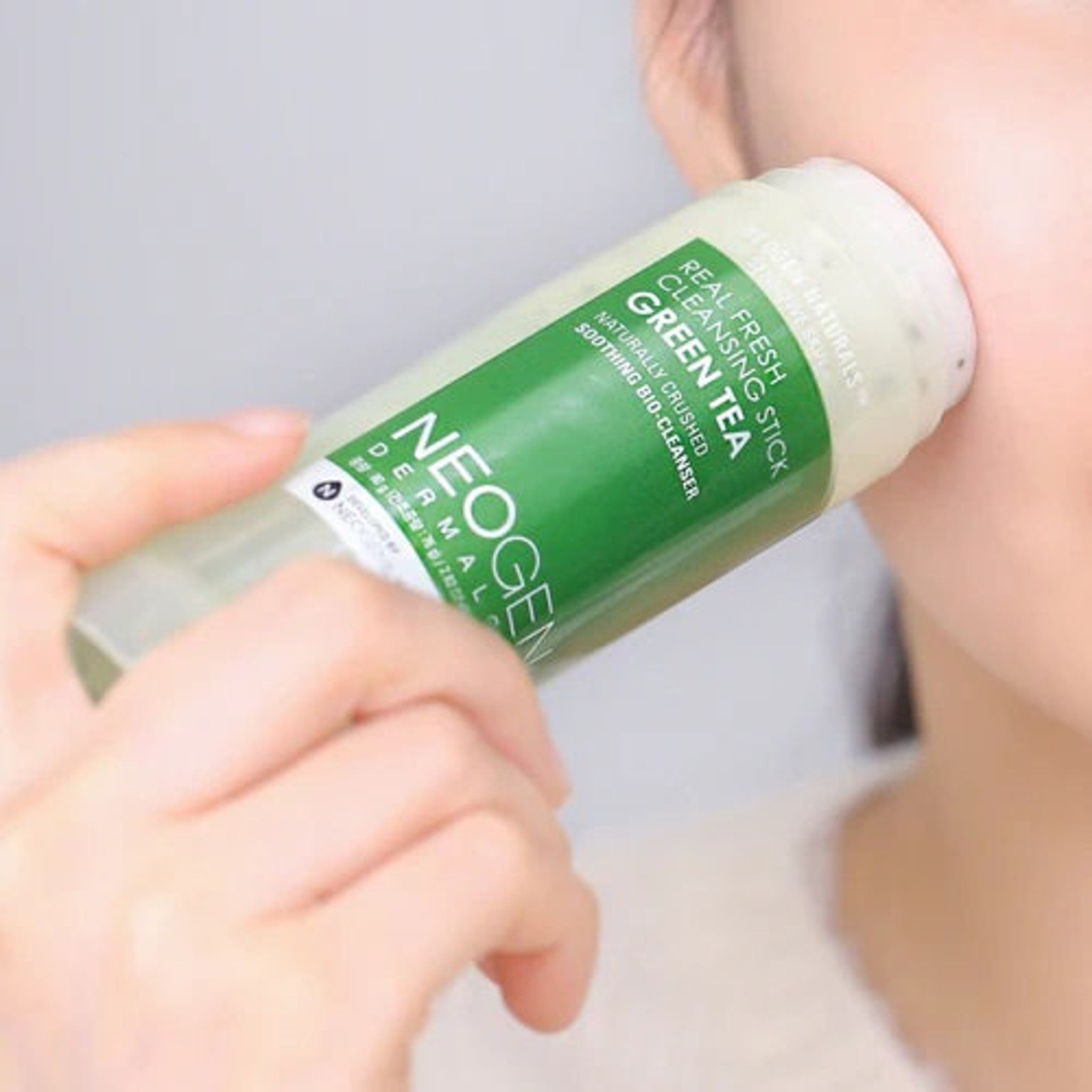 Cleansing stick with green and white label, being used on skin, NEOGEN brand visible